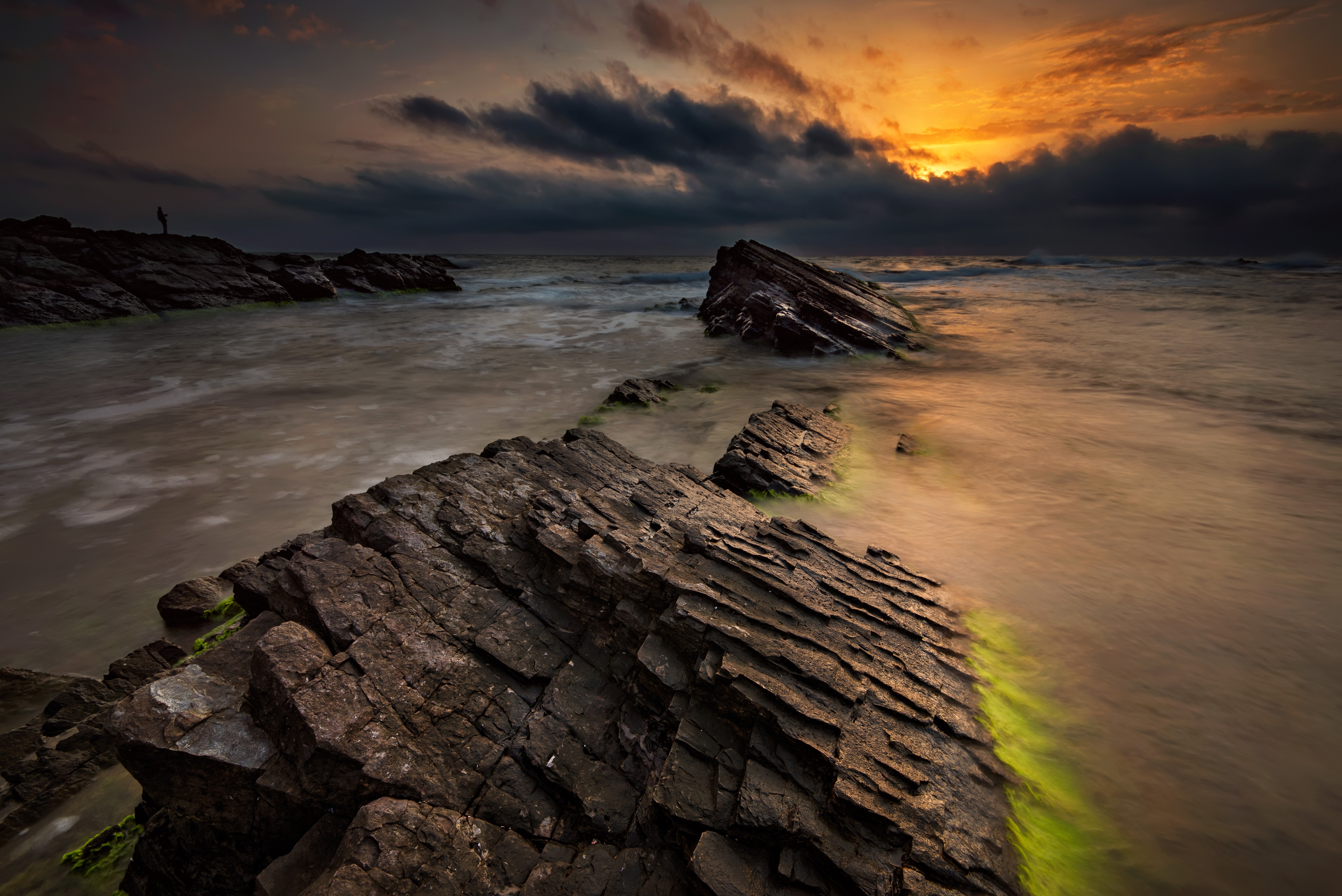 Sunset over rocky coast with person silhouette HD Wallpaper
