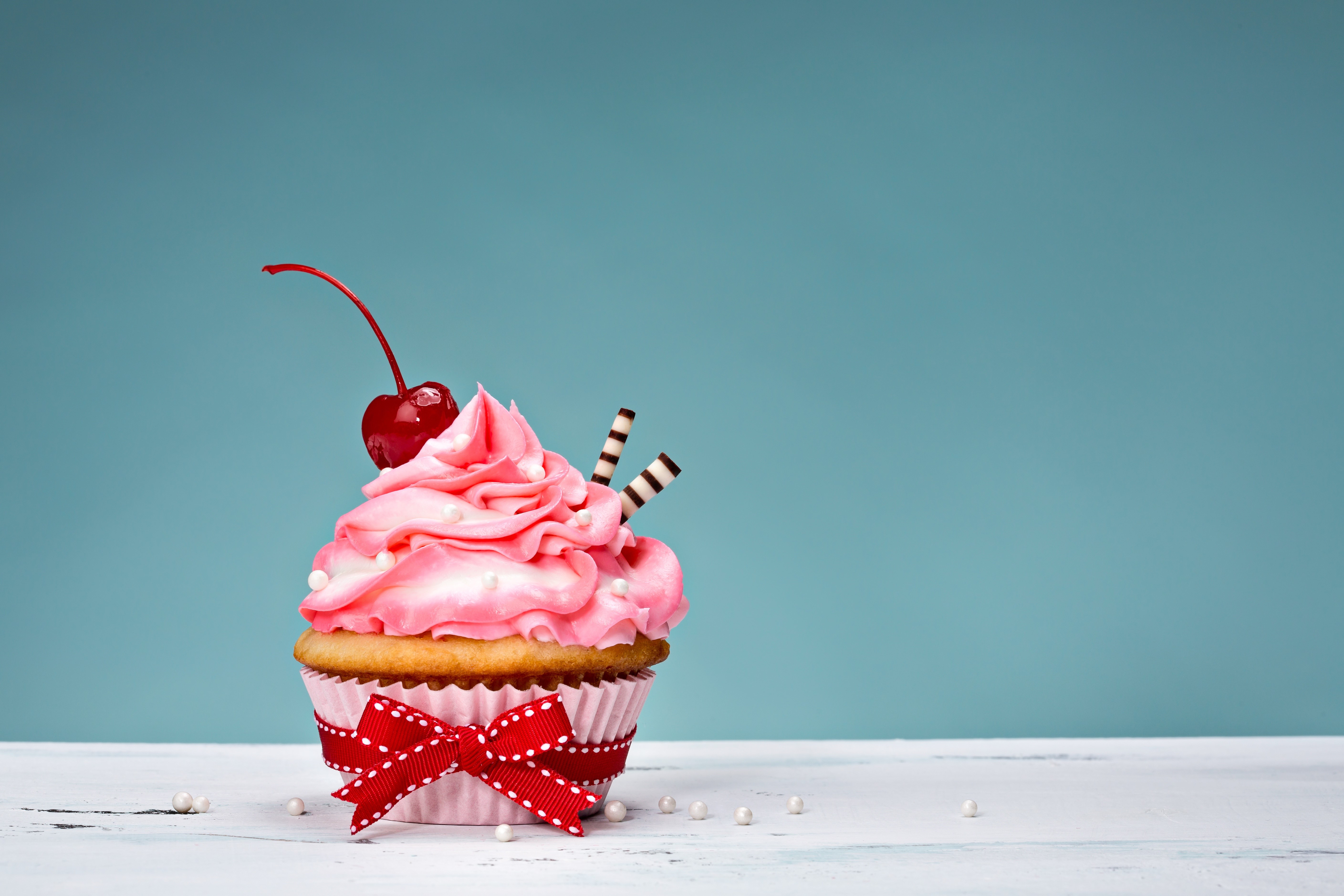 Cupcake with pink frosting, cherry, and red bow HD Wallpaper