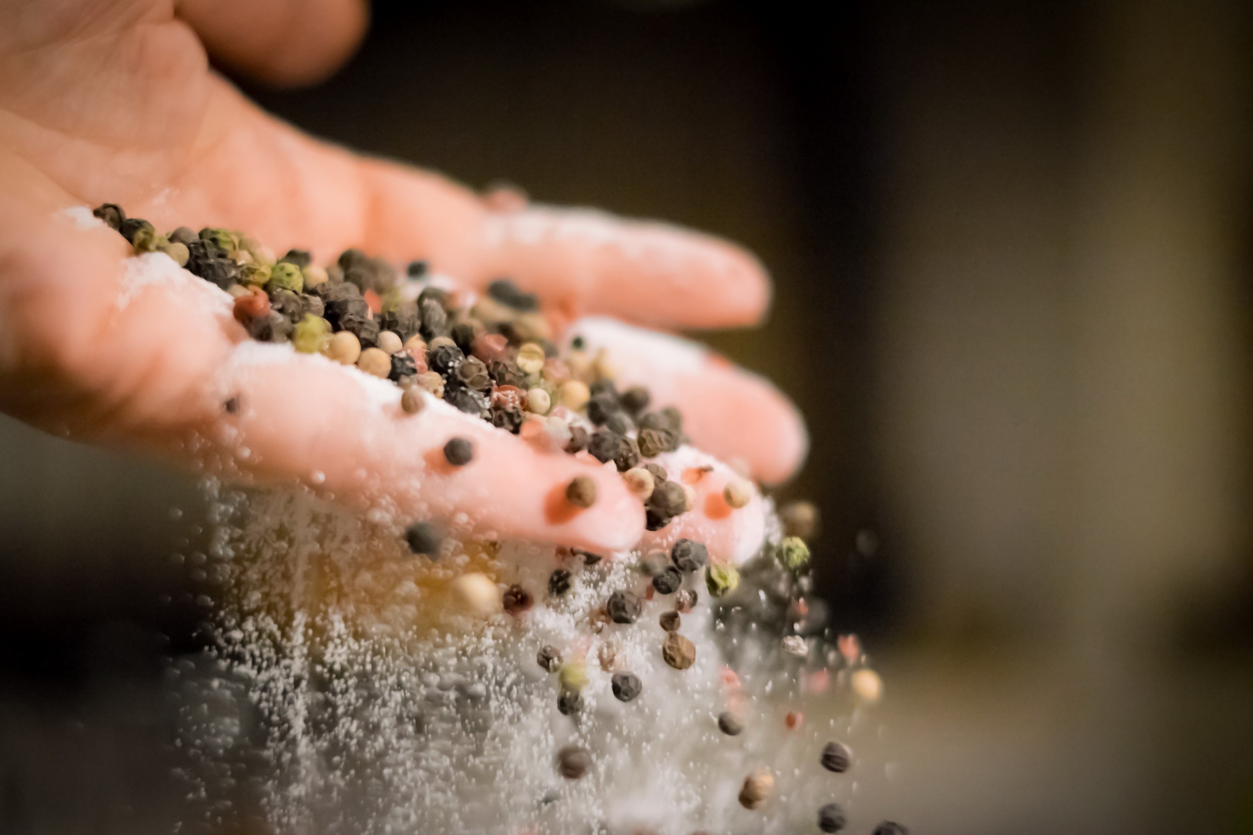 Hand pouring peppercorns and salt HD Wallpaper