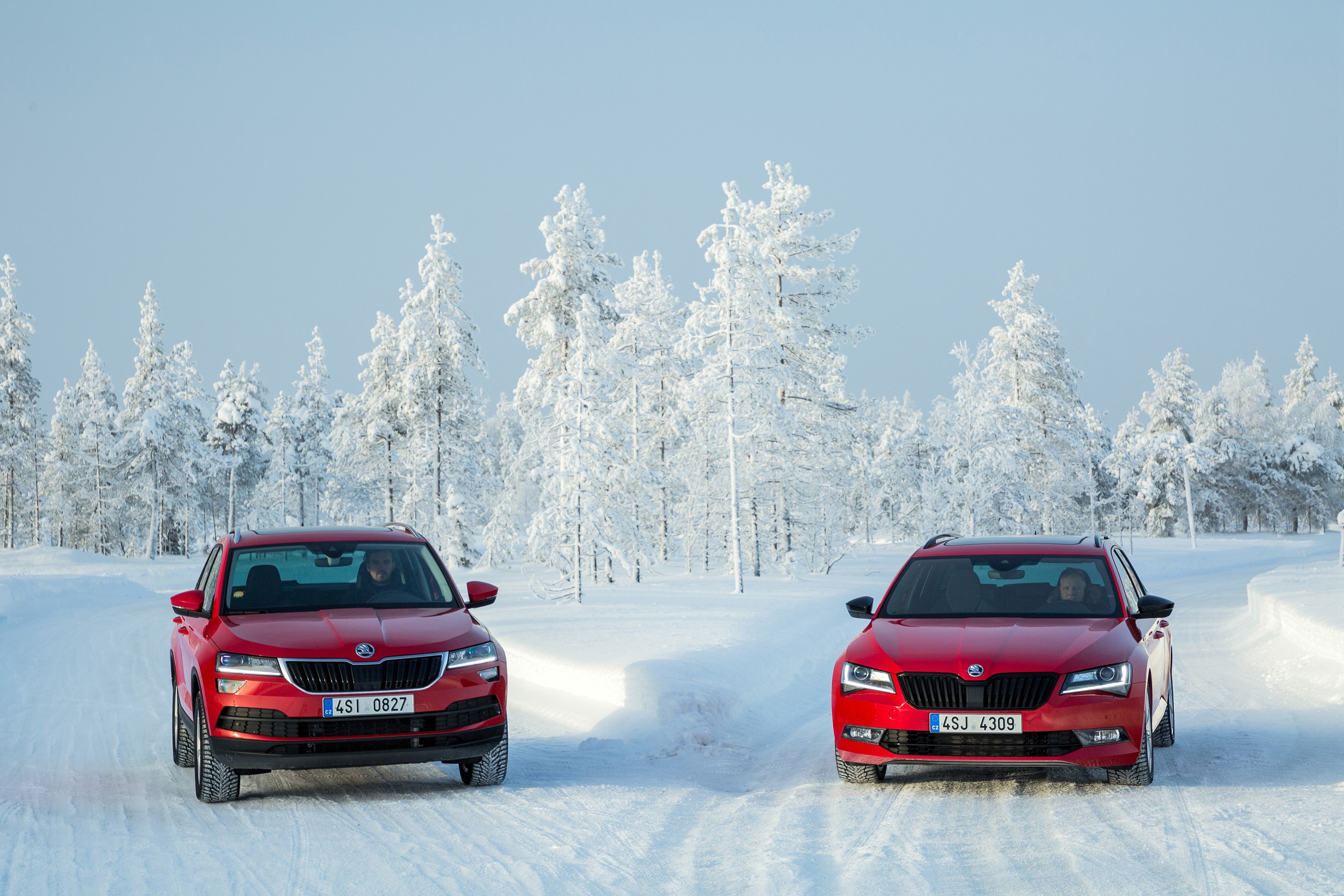 Two red Skoda cars in a snowy forest HD Wallpaper