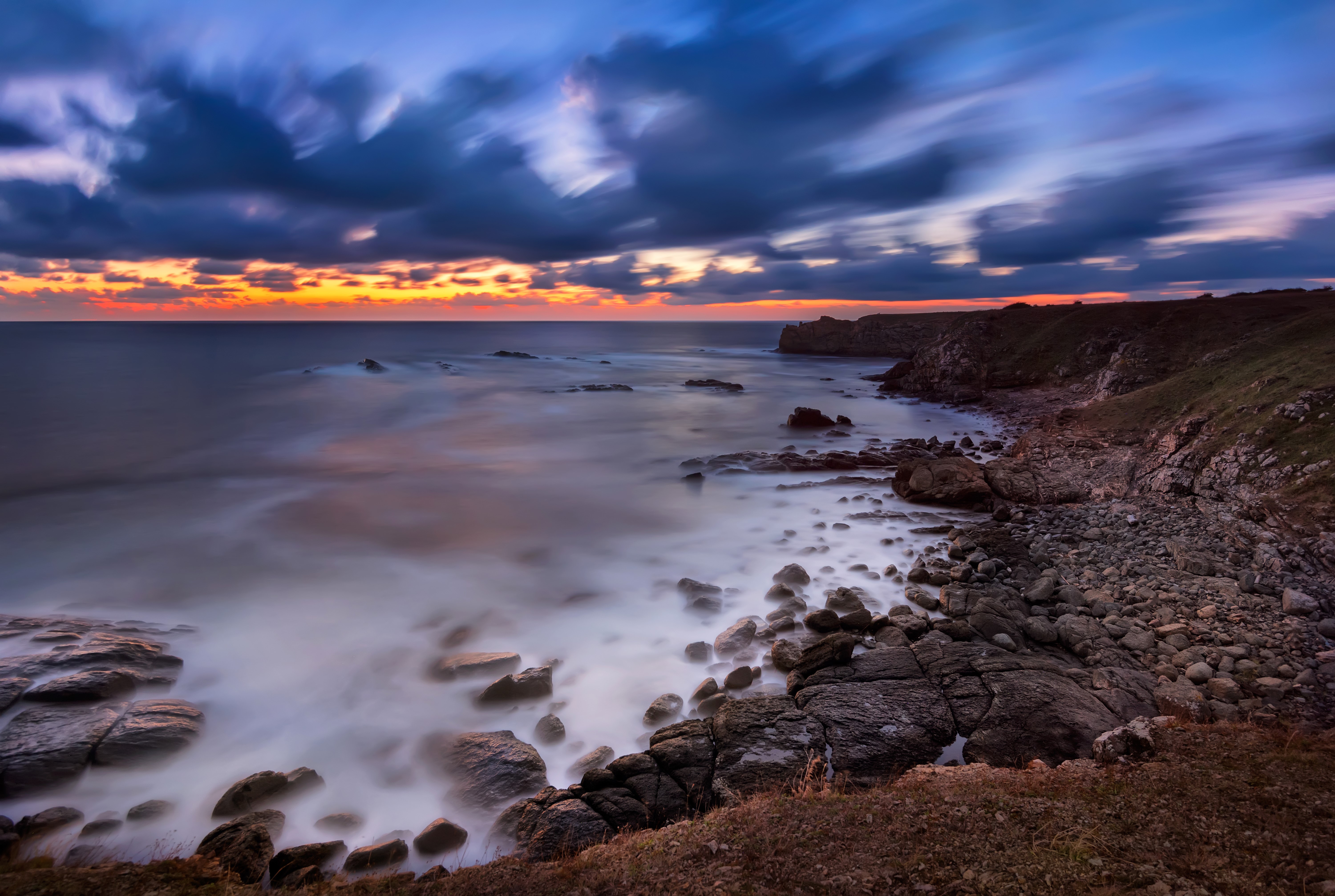 Rocky Coastline at Sunset with Dramatic Clouds HD Wallpaper