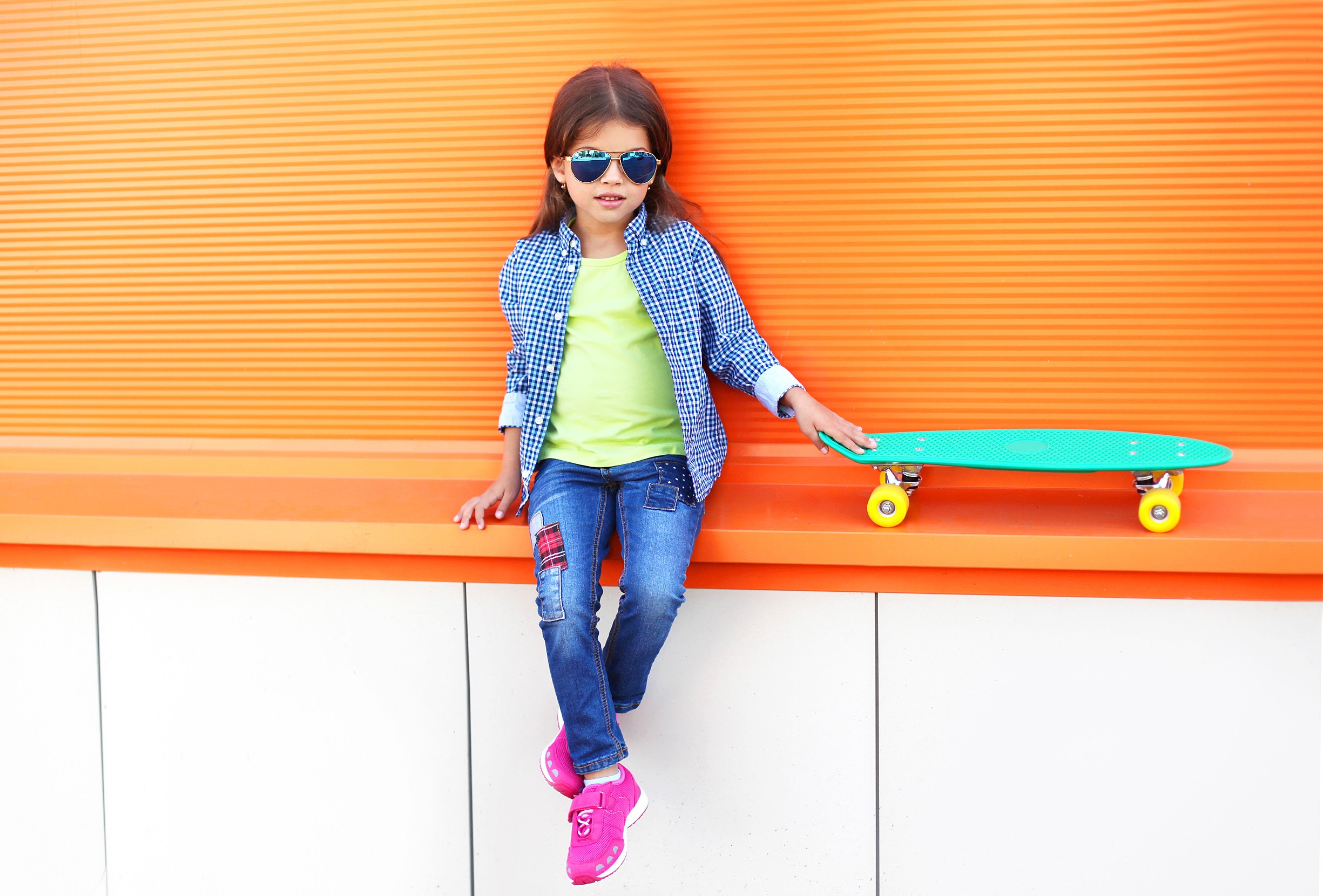 Girl with sunglasses and skateboard sitting on orange bench HD Wallpaper