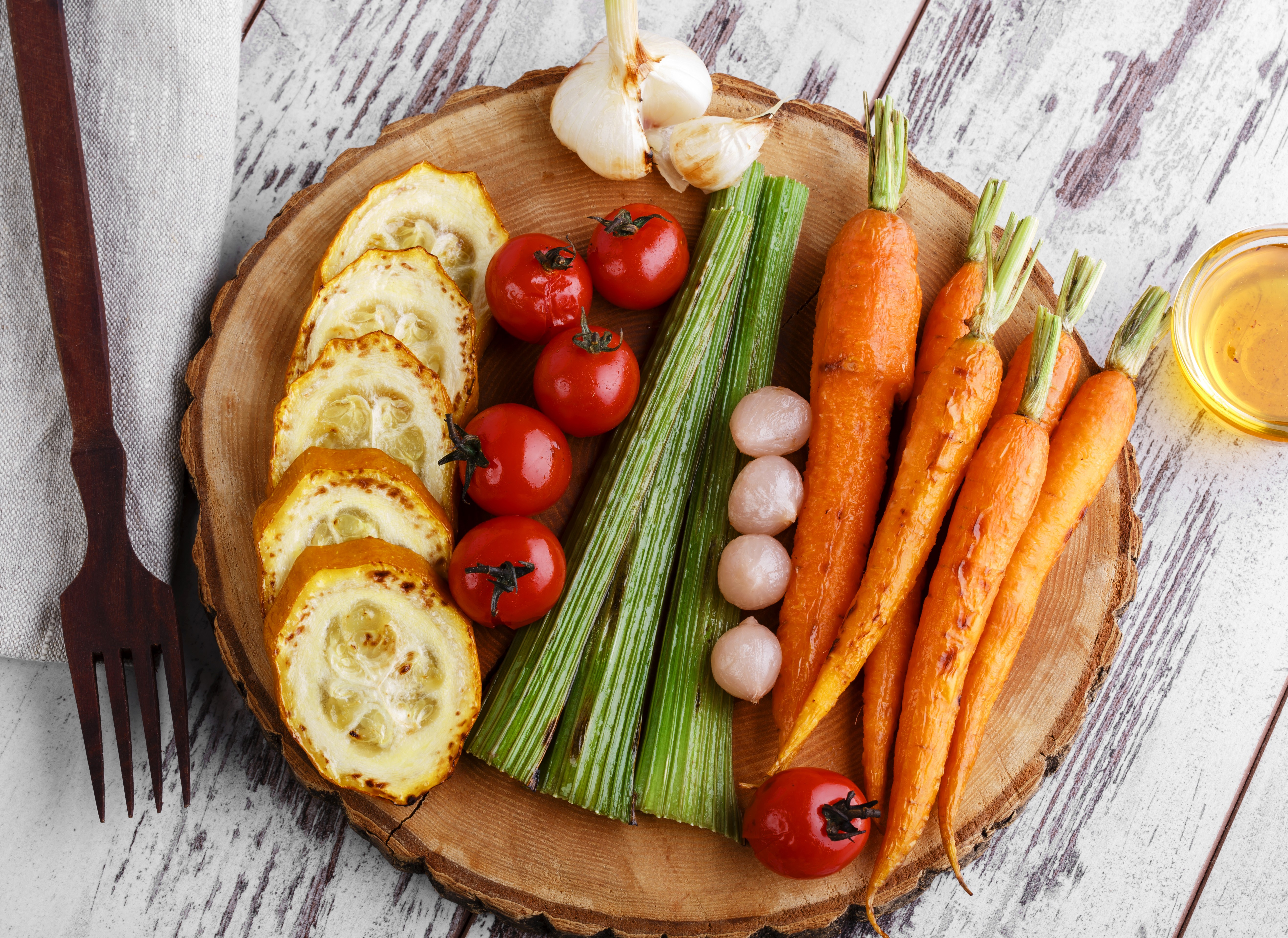 Vegetables including carrots, tomatoes, and garlic on a wooden board HD Wallpaper