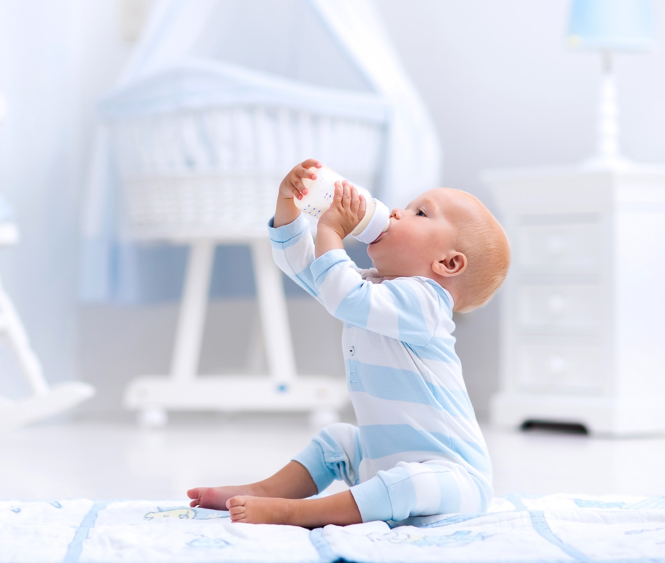Baby drinking from a bottle in a nursery HD Wallpaper
