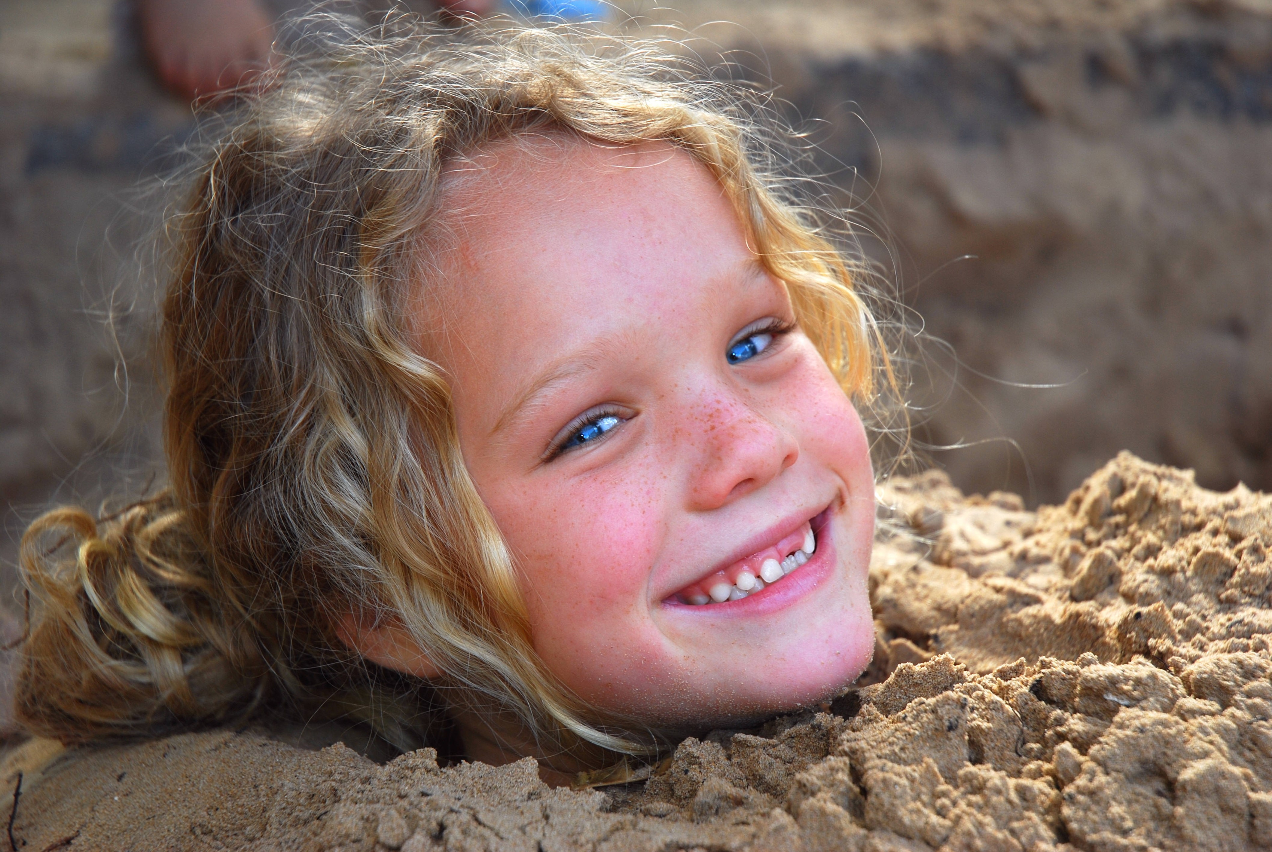 Joyful Little Girl Buried in Sand in 4K HD Wallpaper