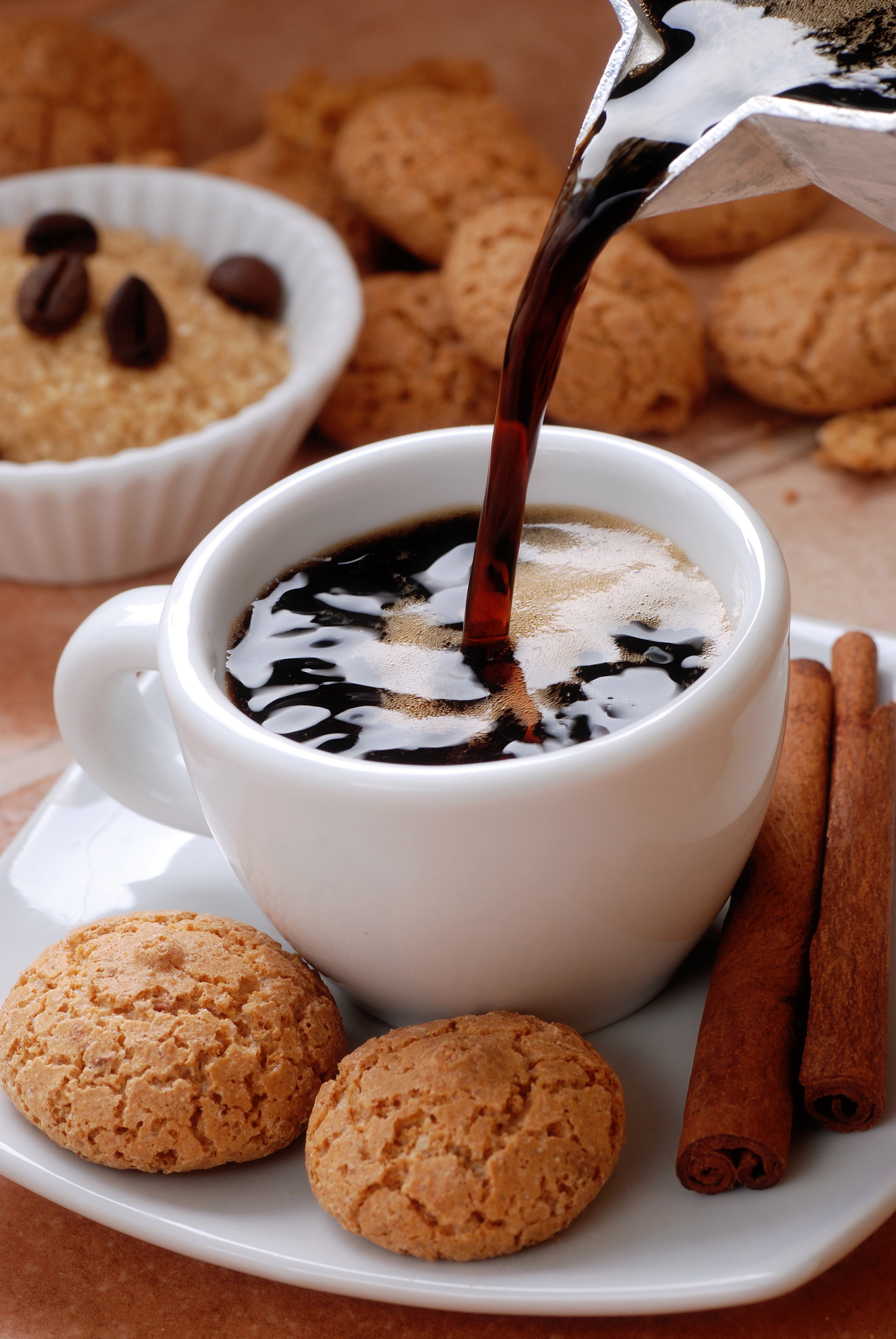 Coffee being poured into a cup with cookies and cinnamon sticks HD Phone Wallpaper