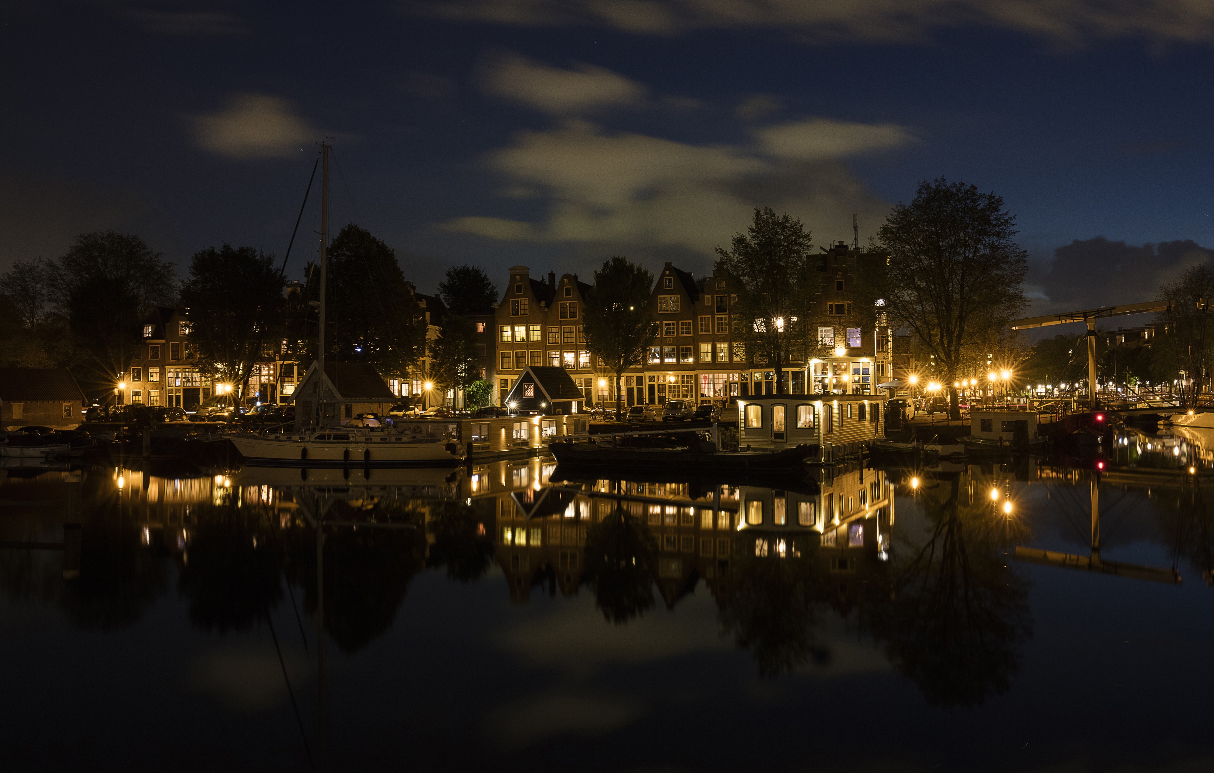 Amsterdam canal at night with illuminated houses and boats HD Wallpaper