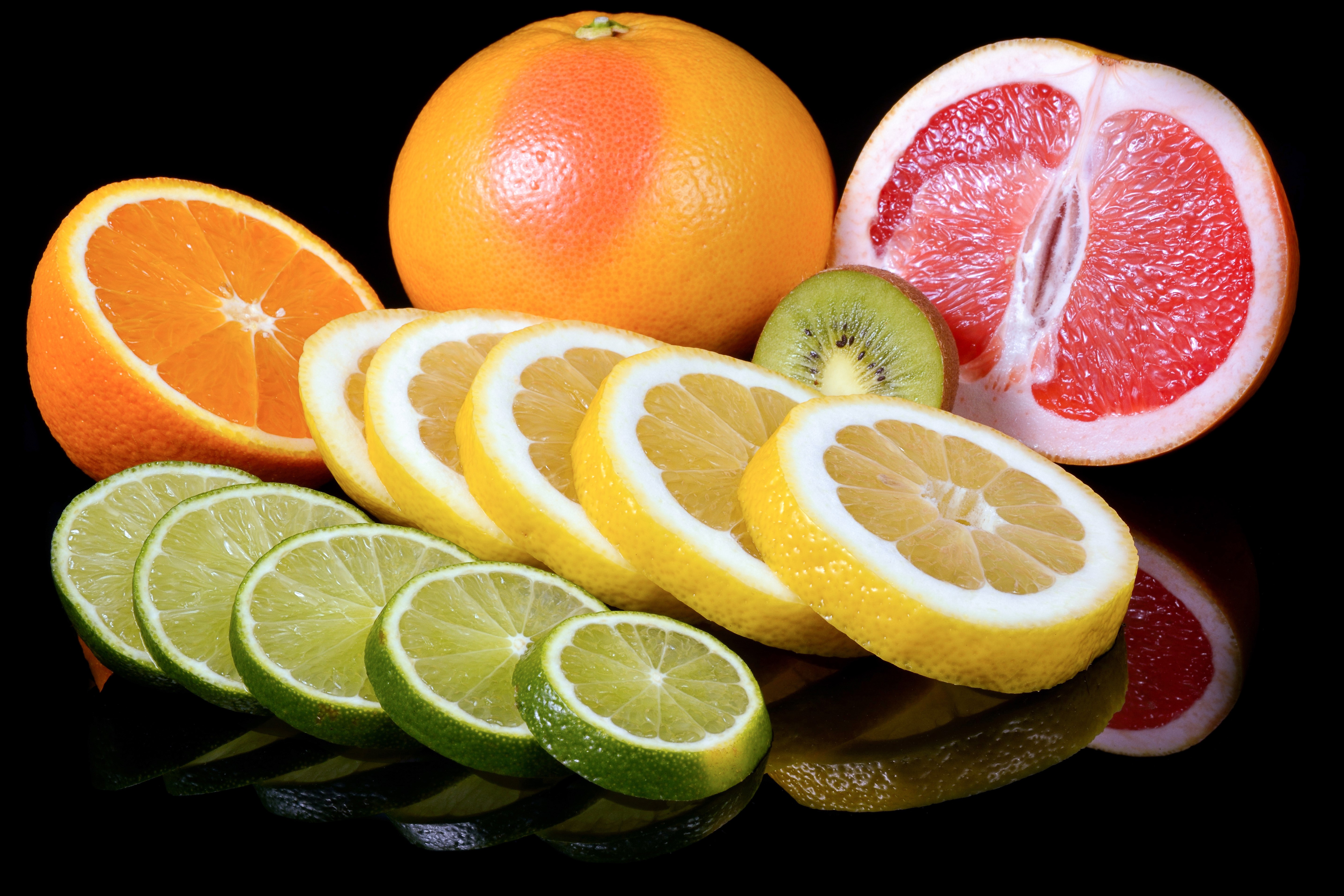 Citrus fruits: orange, grapefruit, lemons, limes, and kiwi on black background HD Wallpaper