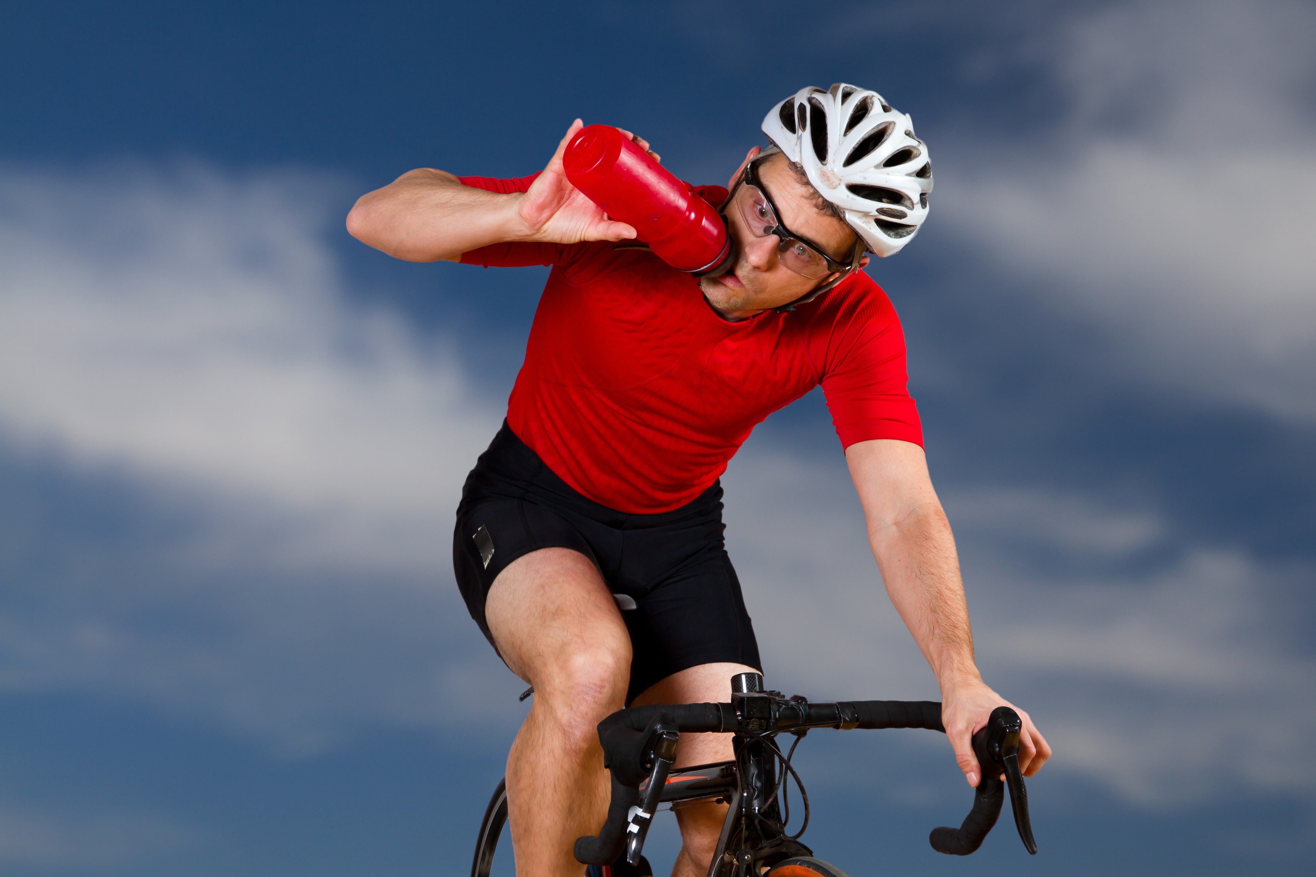 Cyclist in red drinking from a red bottle HD Wallpaper