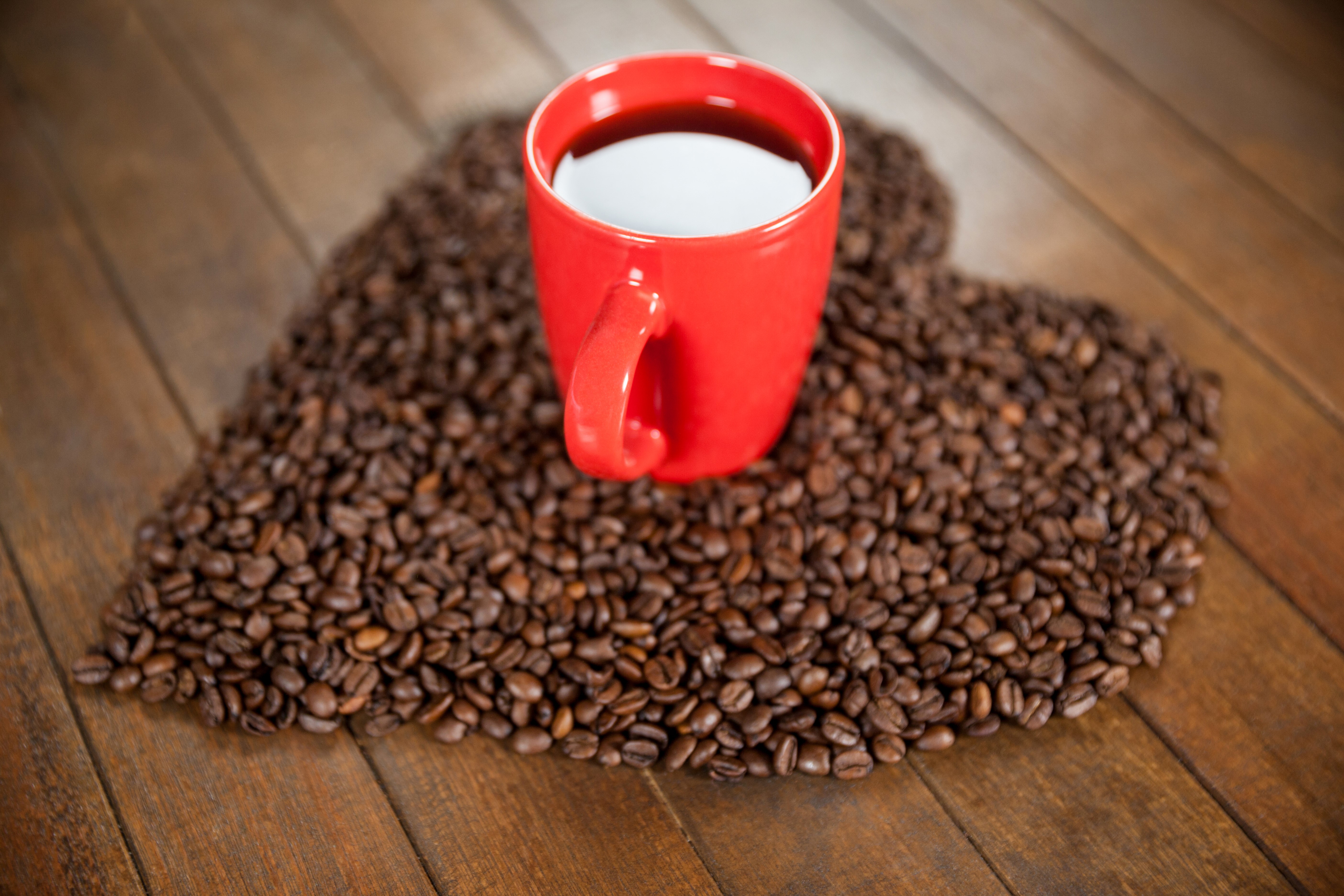 Red coffee cup on heart-shaped coffee beans HD Wallpaper