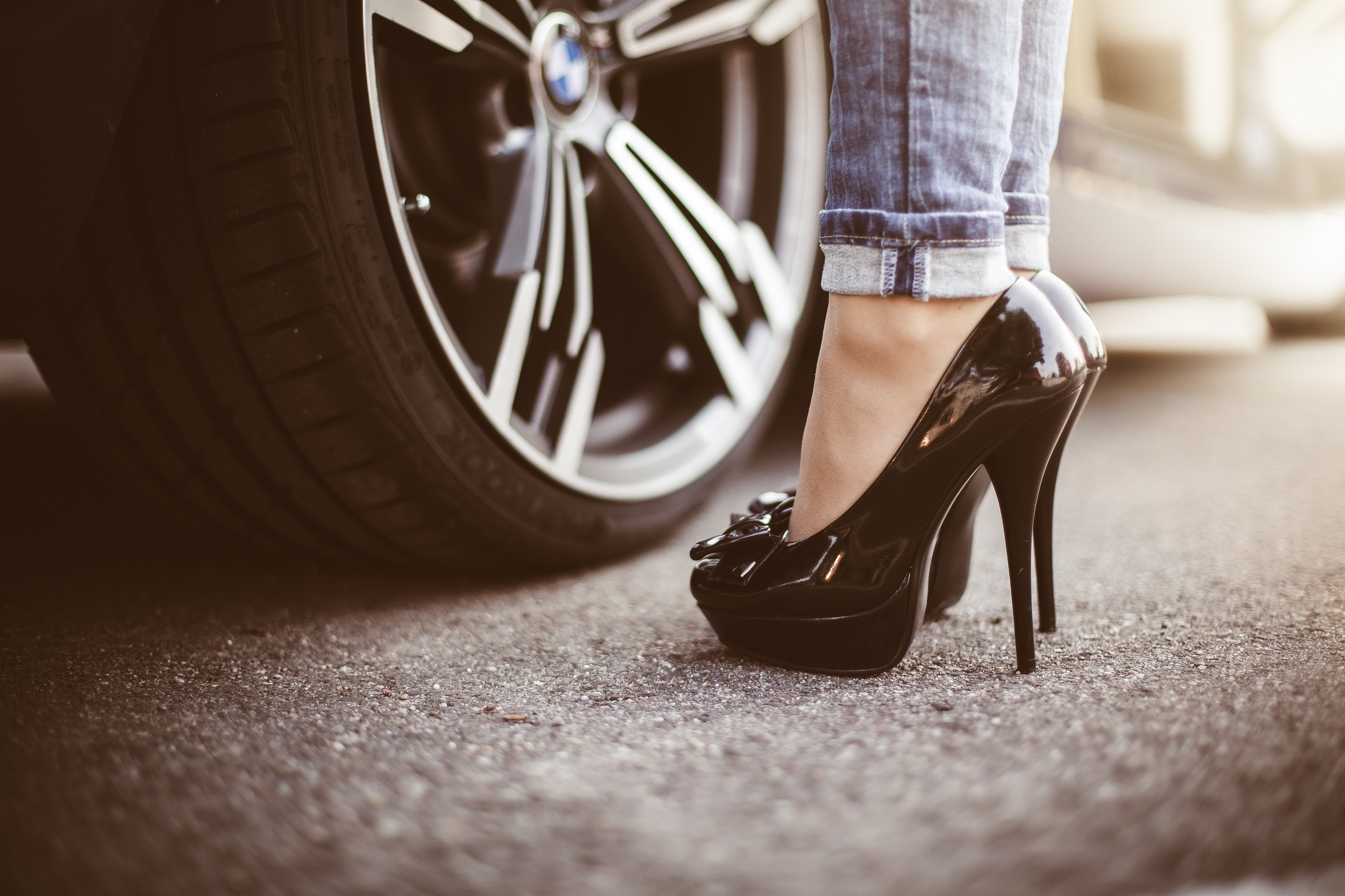 Woman in black stilettos and jeans next to BMW wheel HD Wallpaper
