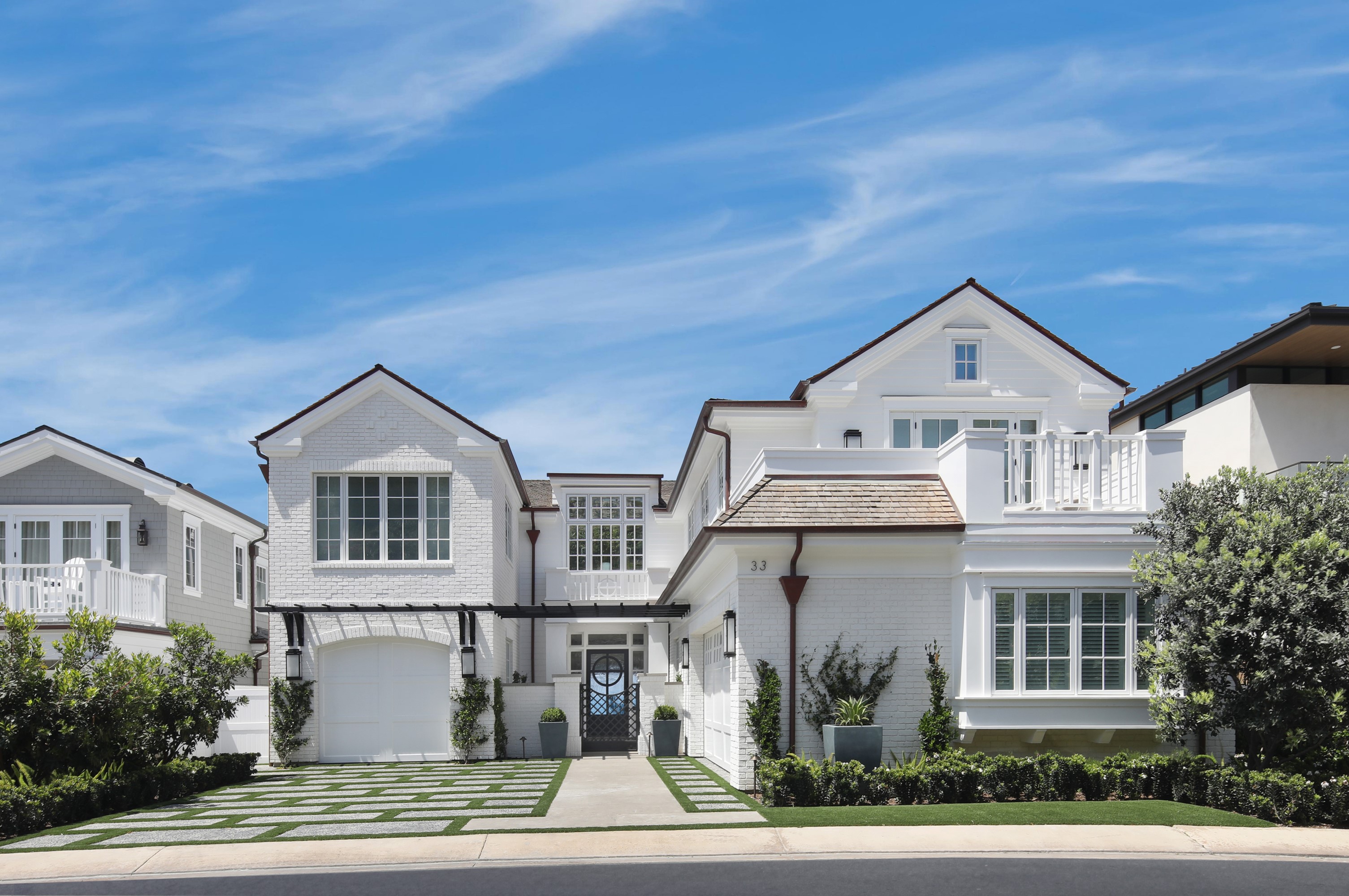 White brick house with garage and blue sky in Dana Point HD Wallpaper