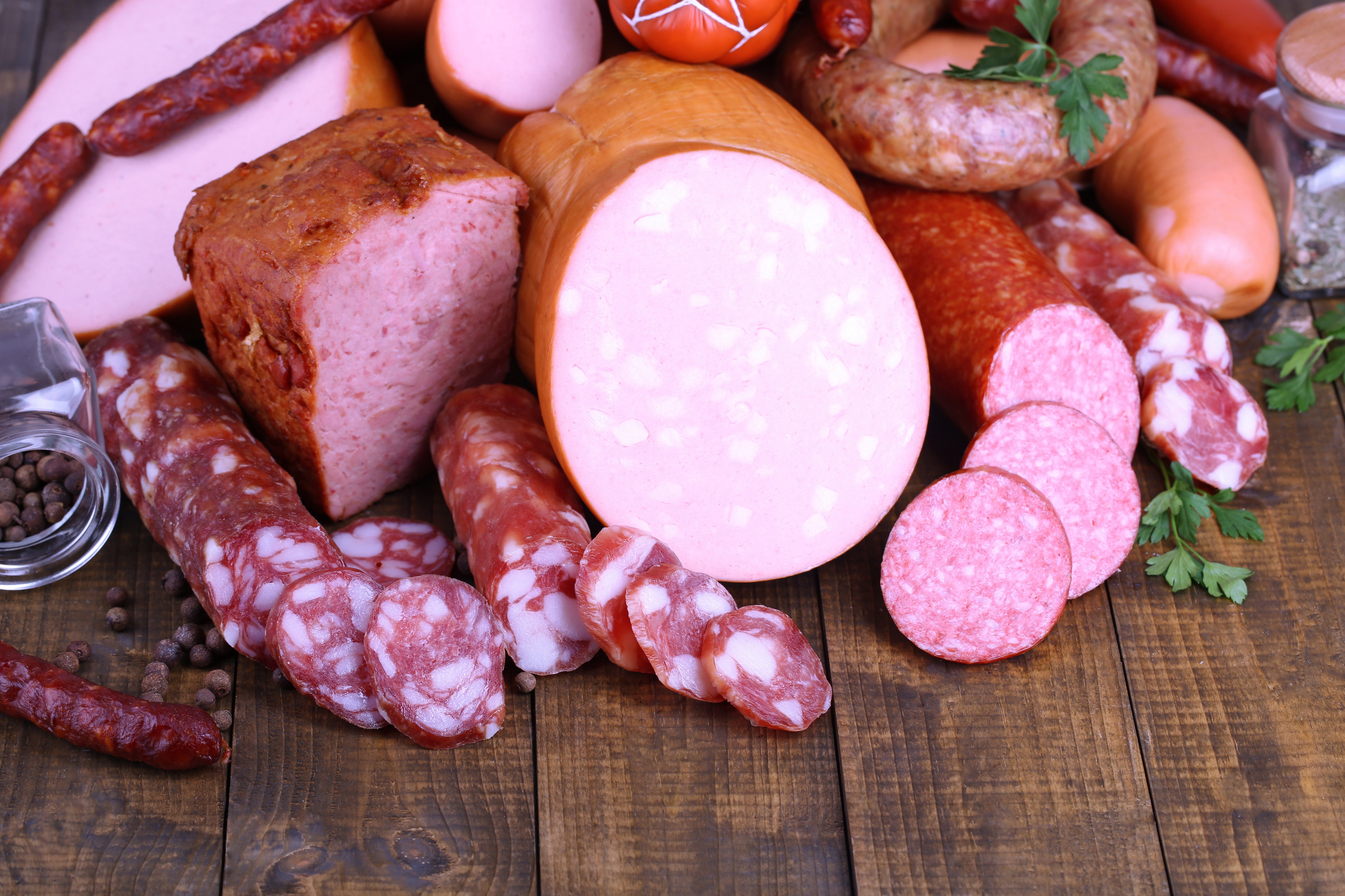 Assortment of sausages and meat products on wooden planks HD Wallpaper