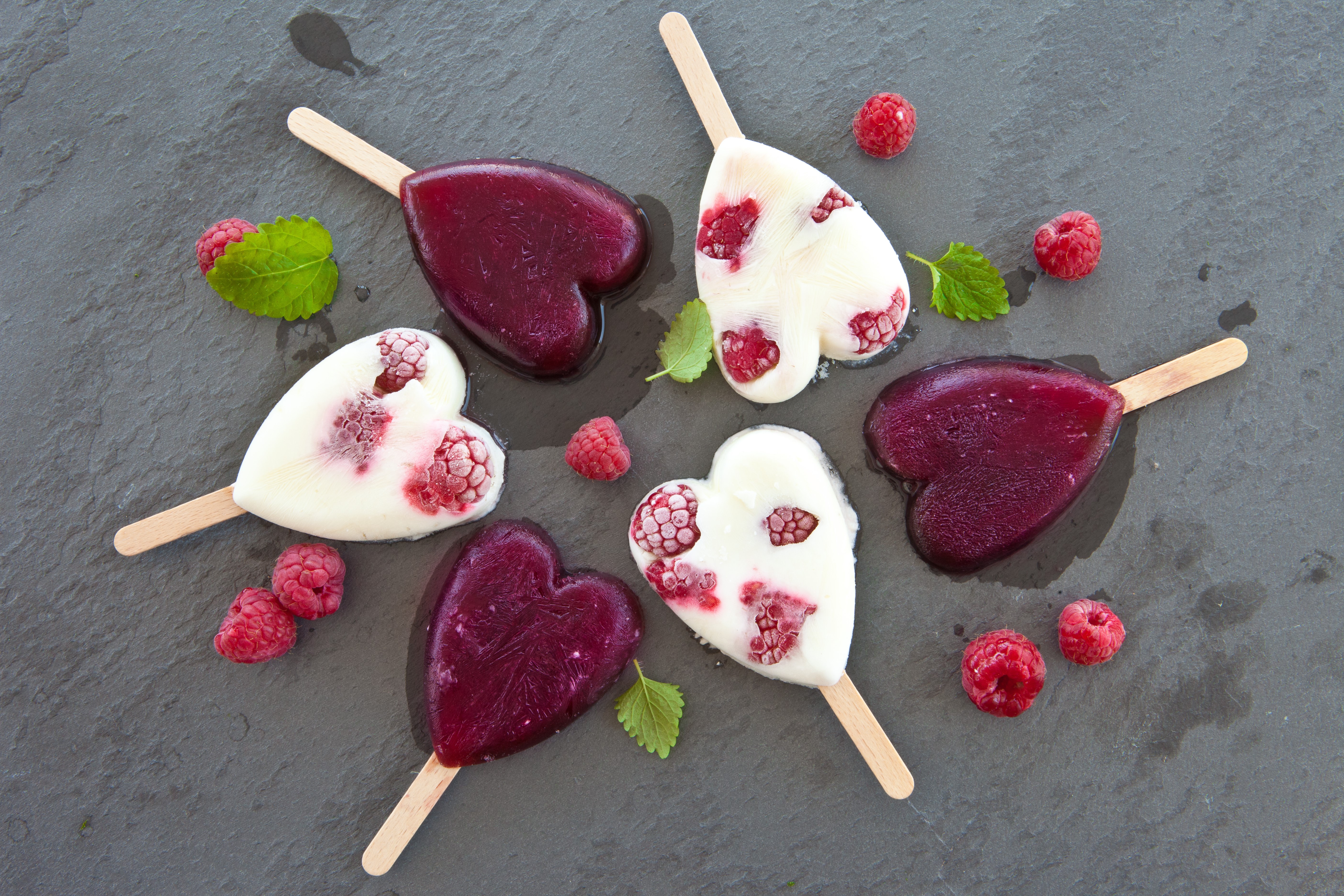 Heart-shaped raspberry ice pops on a slate surface HD Wallpaper