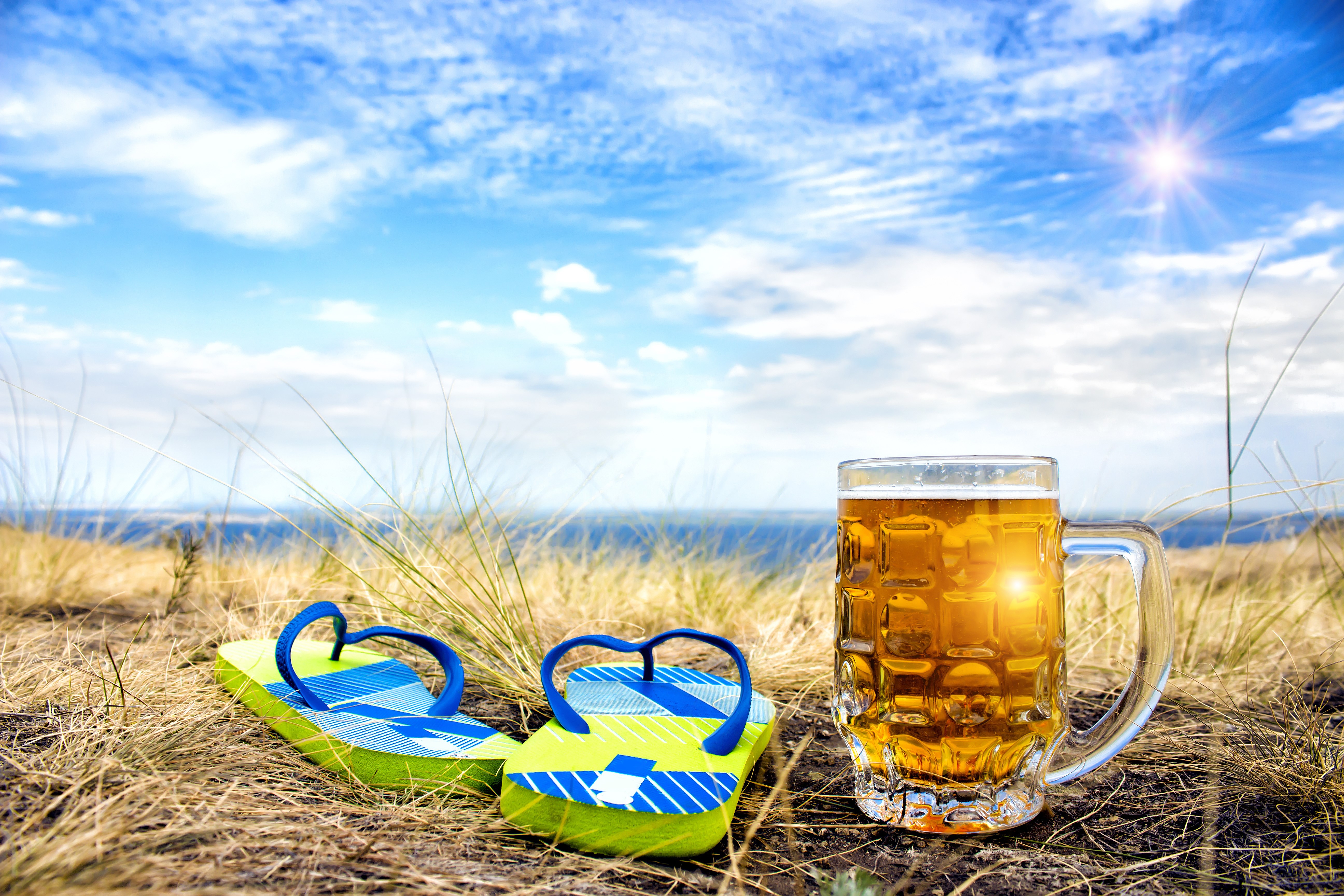 Beer mug and flip-flops on beach with blue sky HD Wallpaper