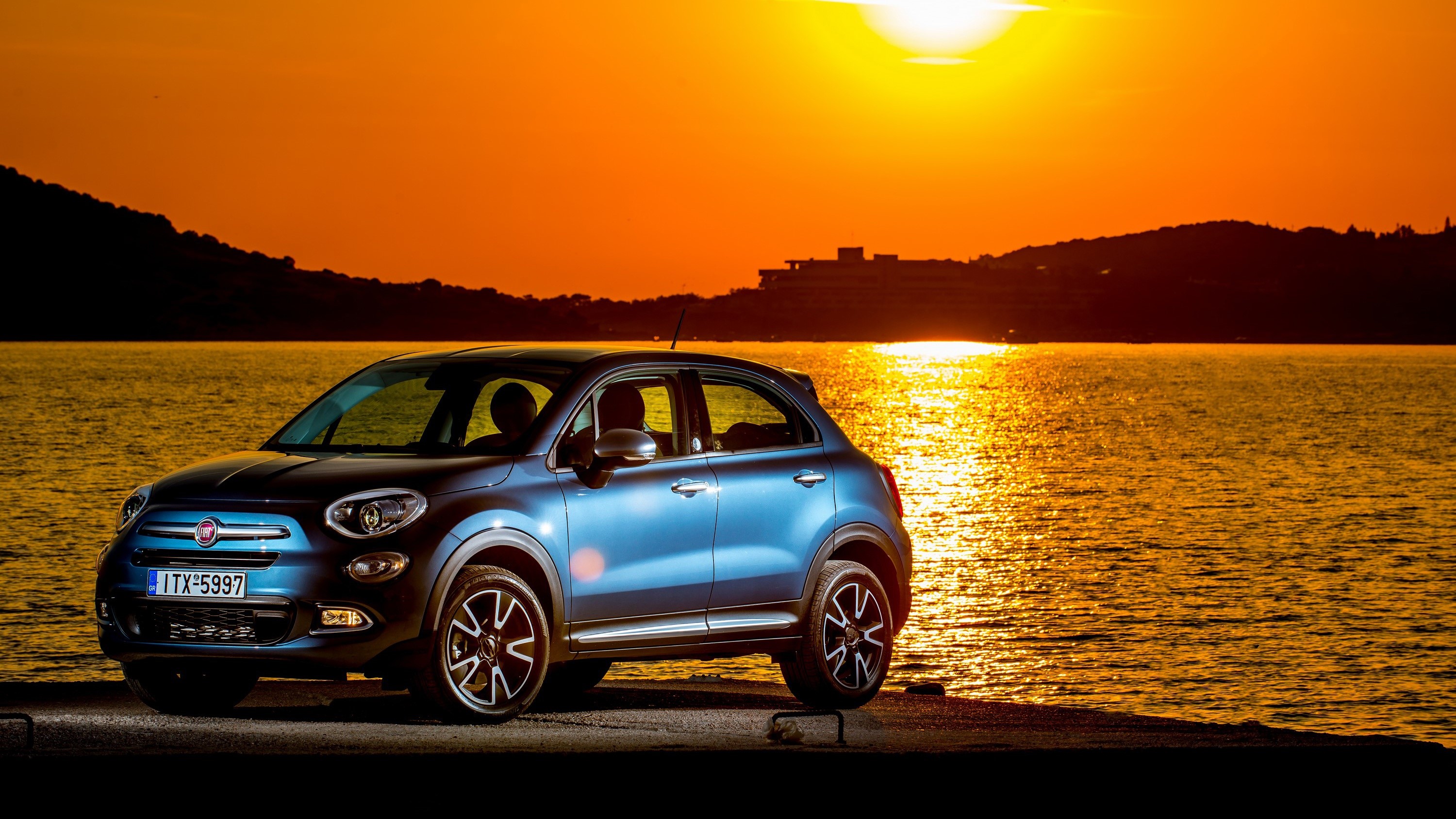Blue Fiat 500X parked by the sea at sunset HD Wallpaper