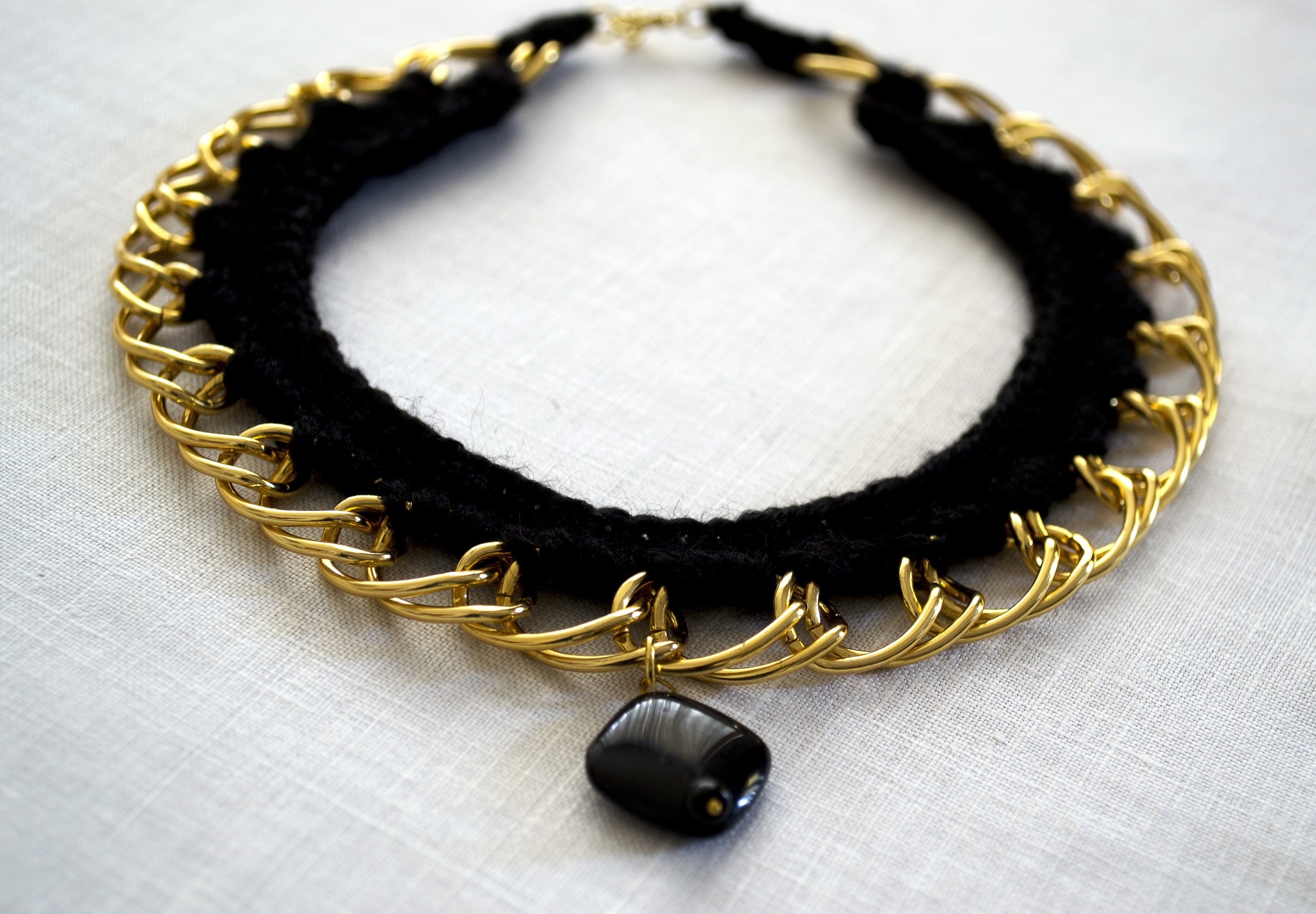 Black knitted necklace with gold chain and black pendant HD Wallpaper