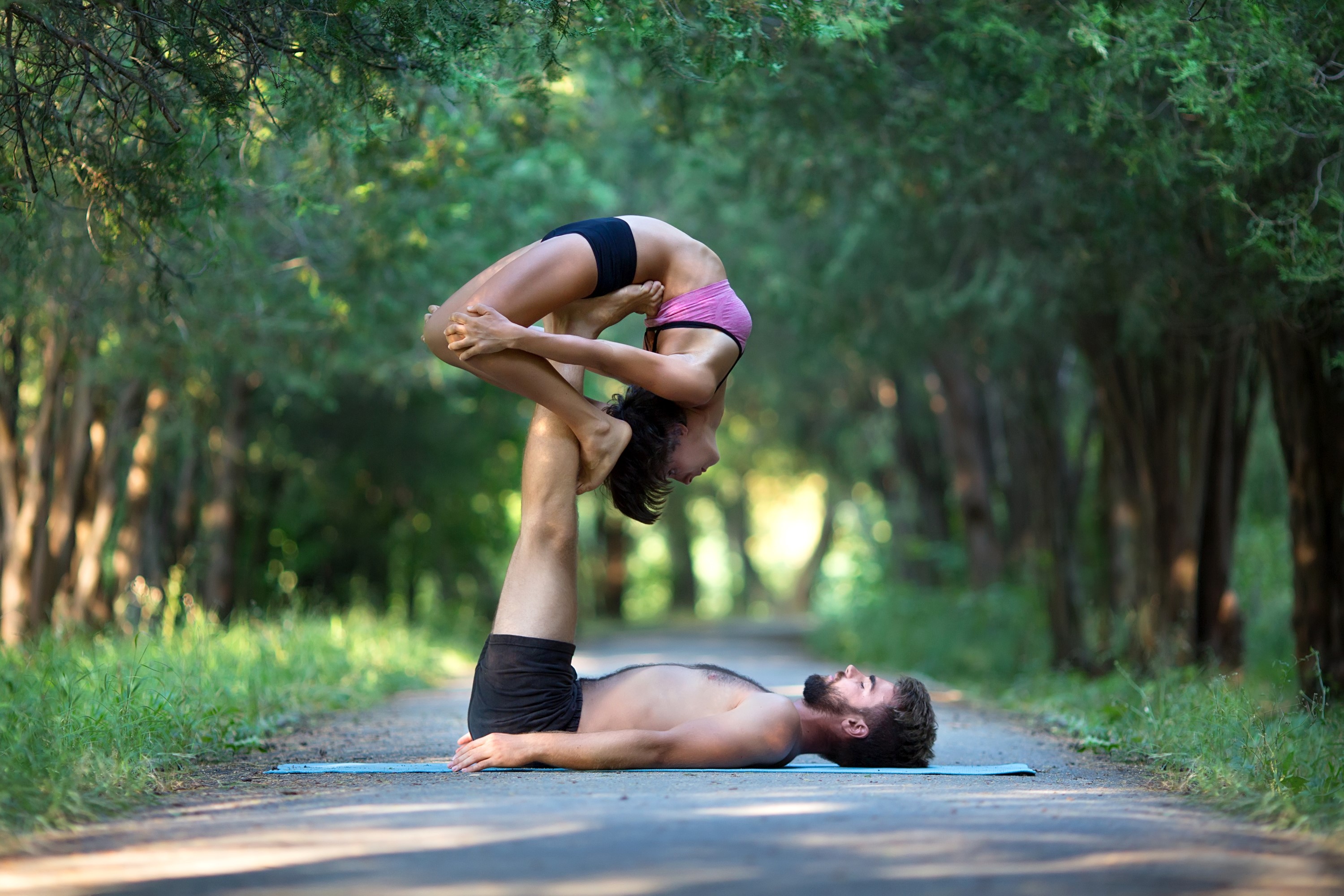 Couple performing acroyoga on a path HD Wallpaper