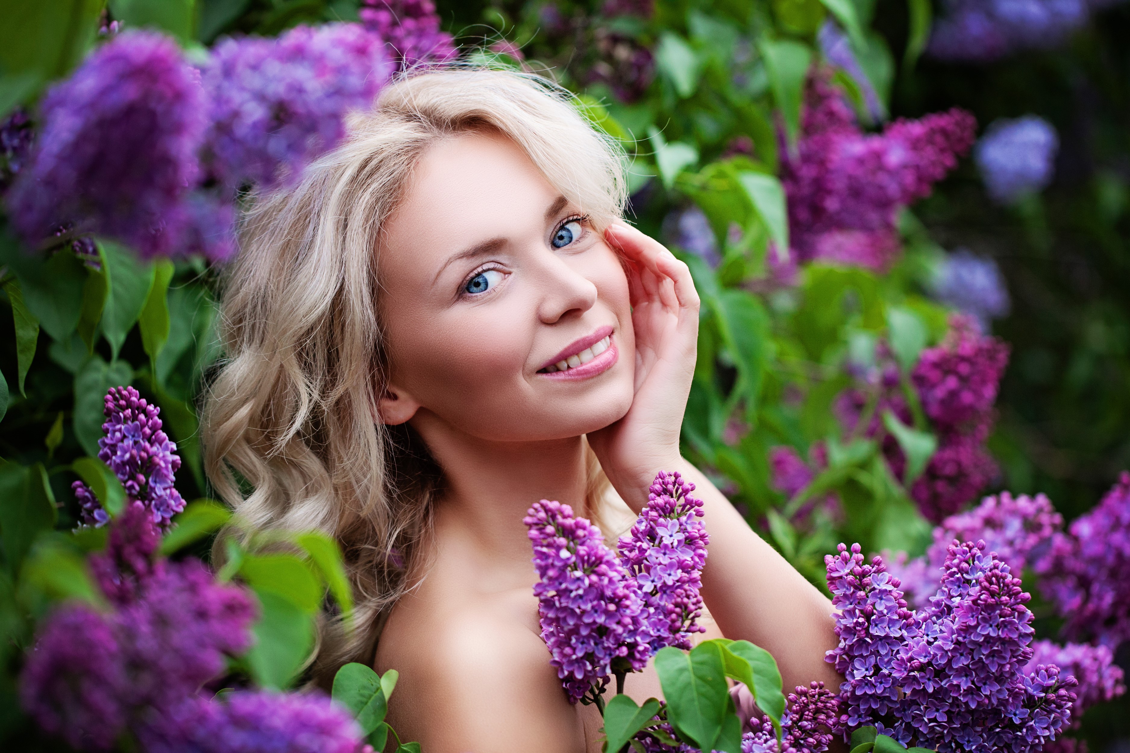 Blonde girl smiling among lilacs HD Wallpaper