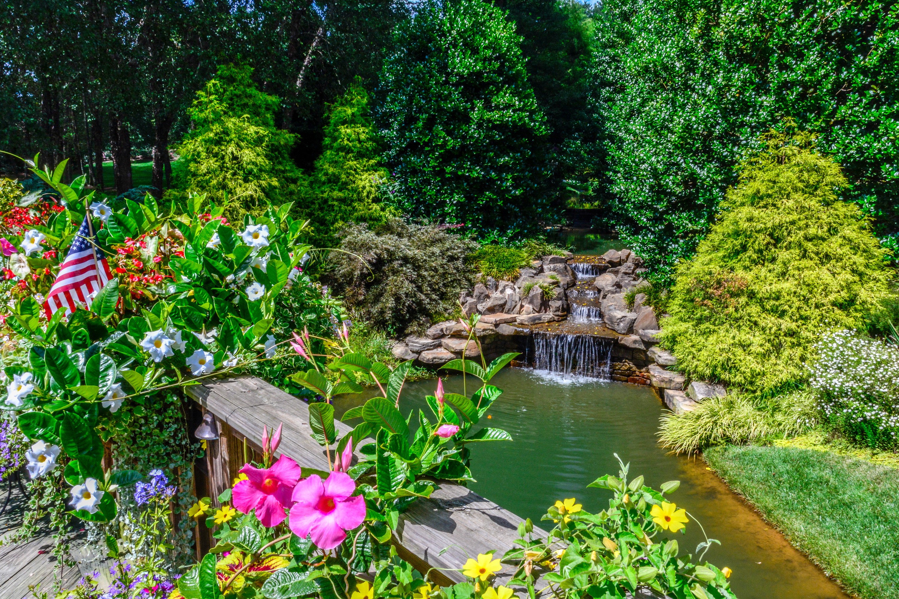 Gibbs Gardens waterfall with American flag and flowers HD Wallpaper