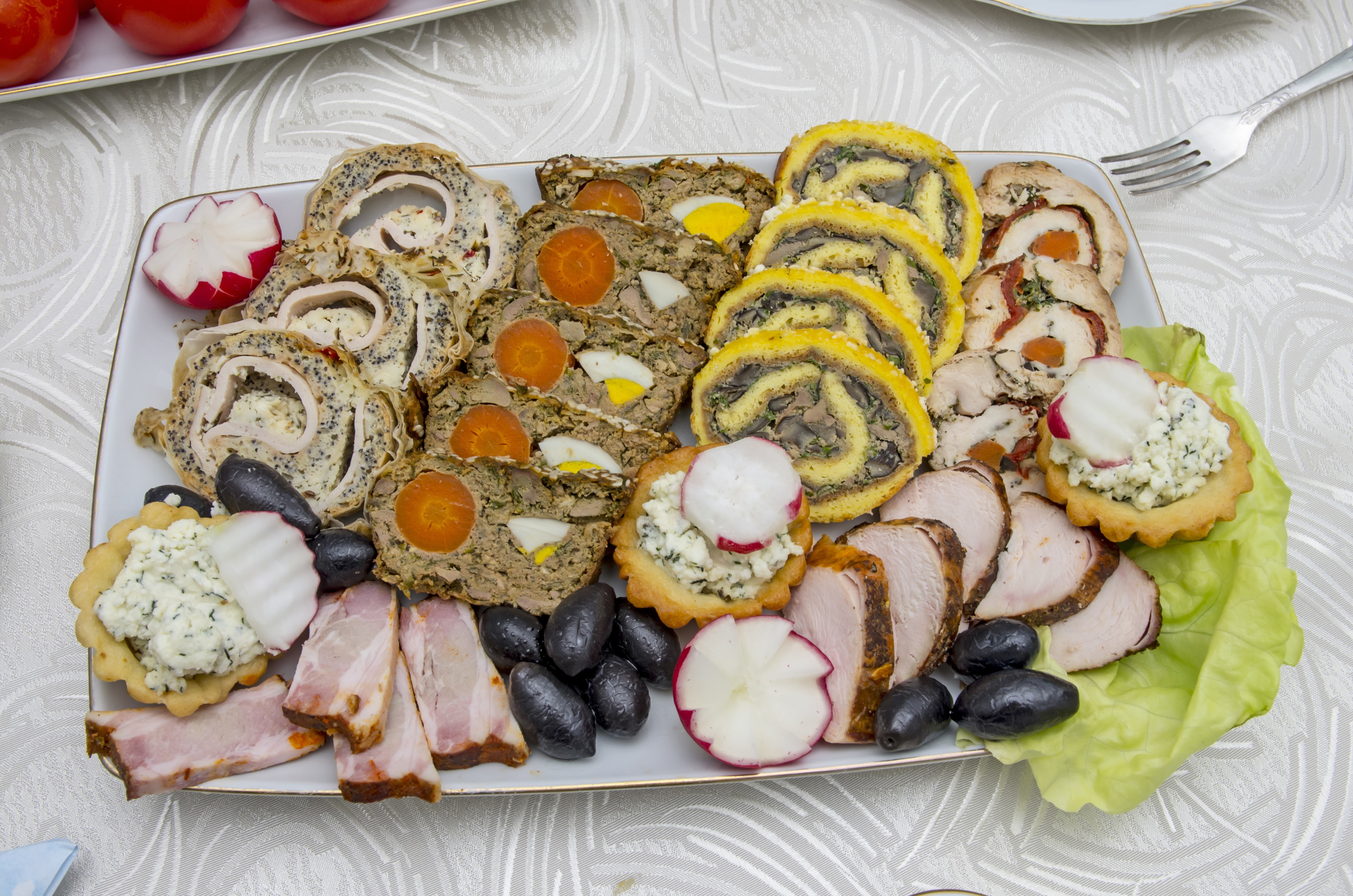Appetizer platter with meat rolls, olives, and radishes HD Wallpaper