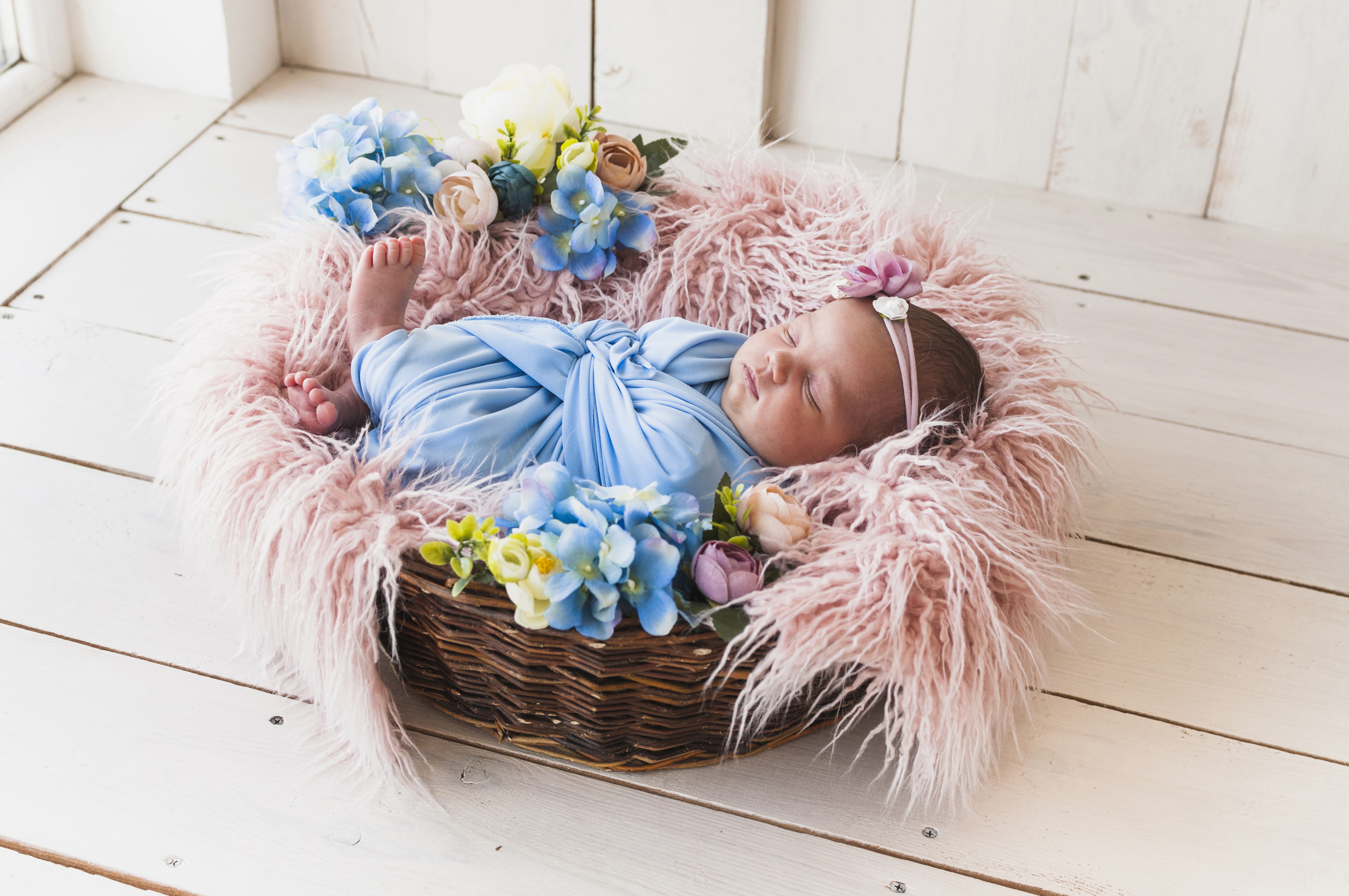 Newborn baby sleeping in a wicker basket with flowers HD Wallpaper