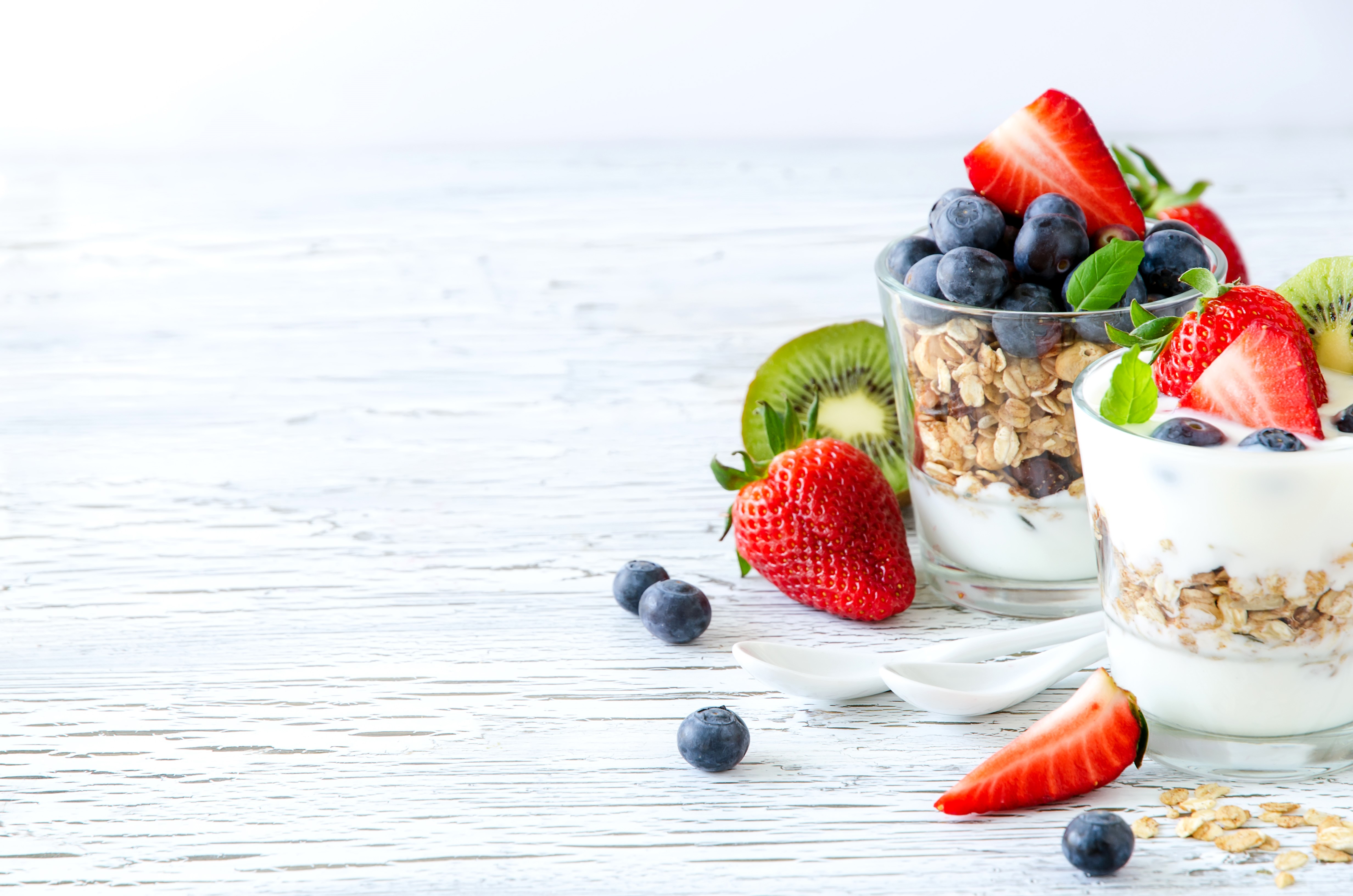 Yogurt parfaits with strawberries, blueberries, and kiwi on wood planks HD Wallpaper