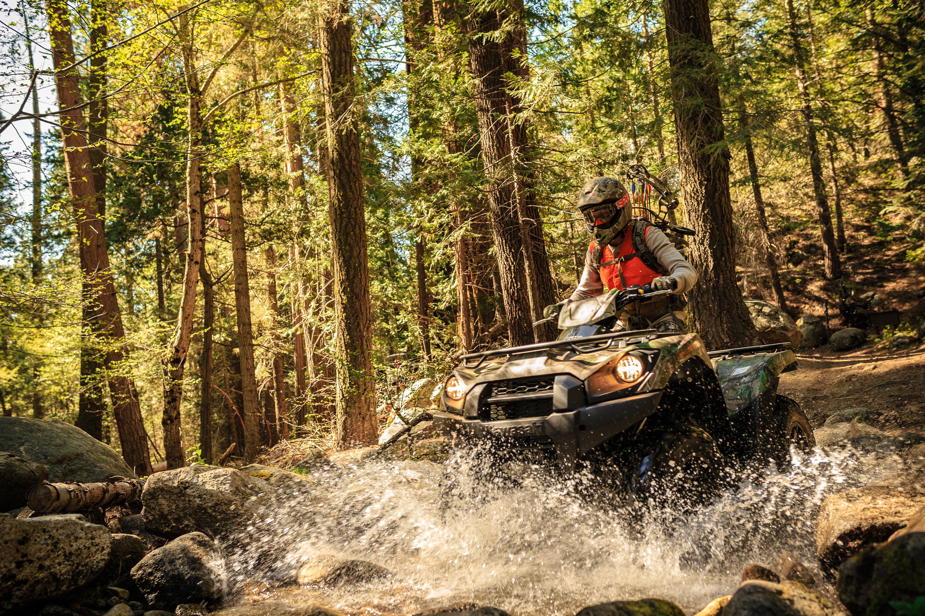 Man riding an ATV through a forest stream HD Wallpaper