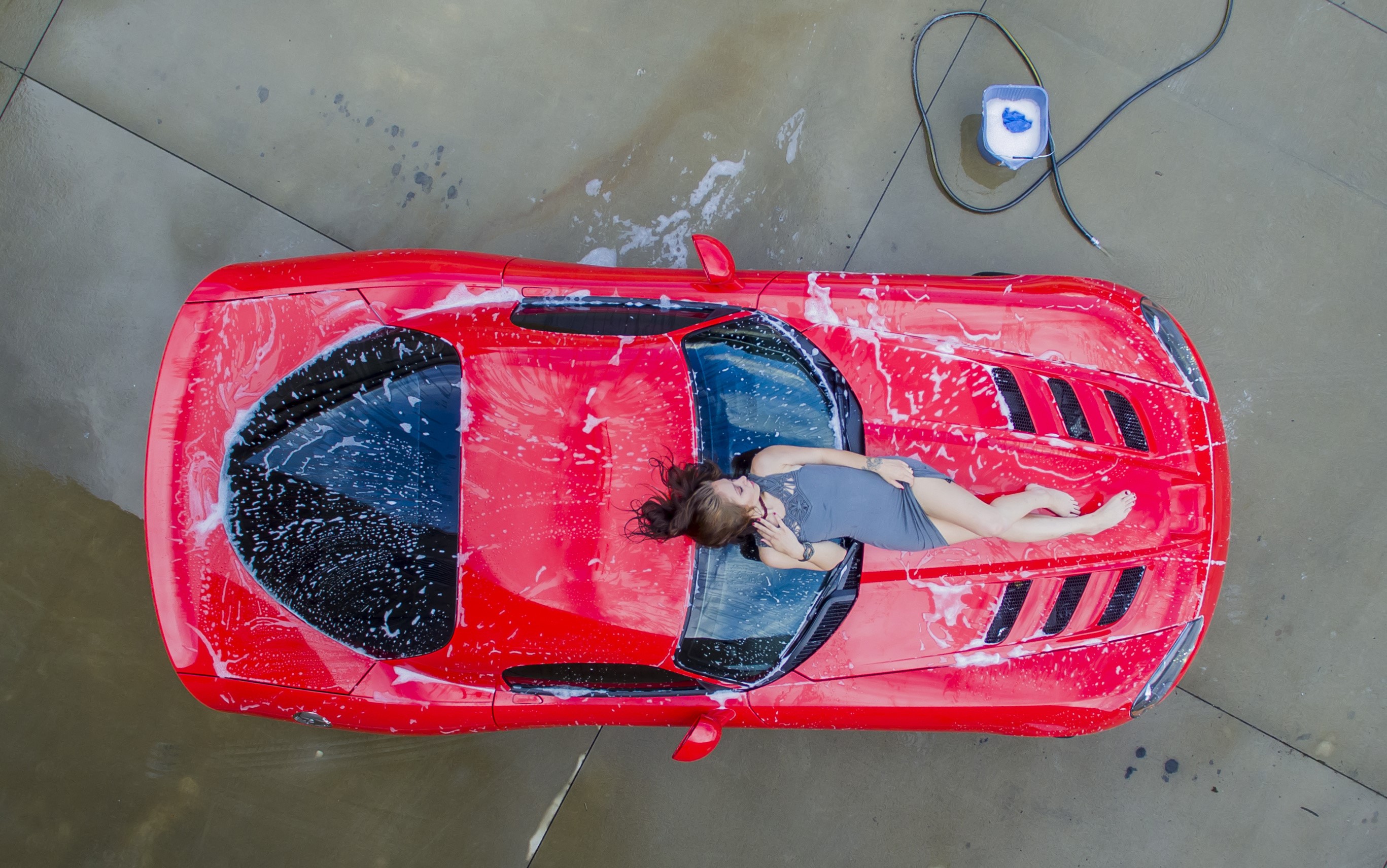 Woman lying on a red car covered in soap HD Wallpaper