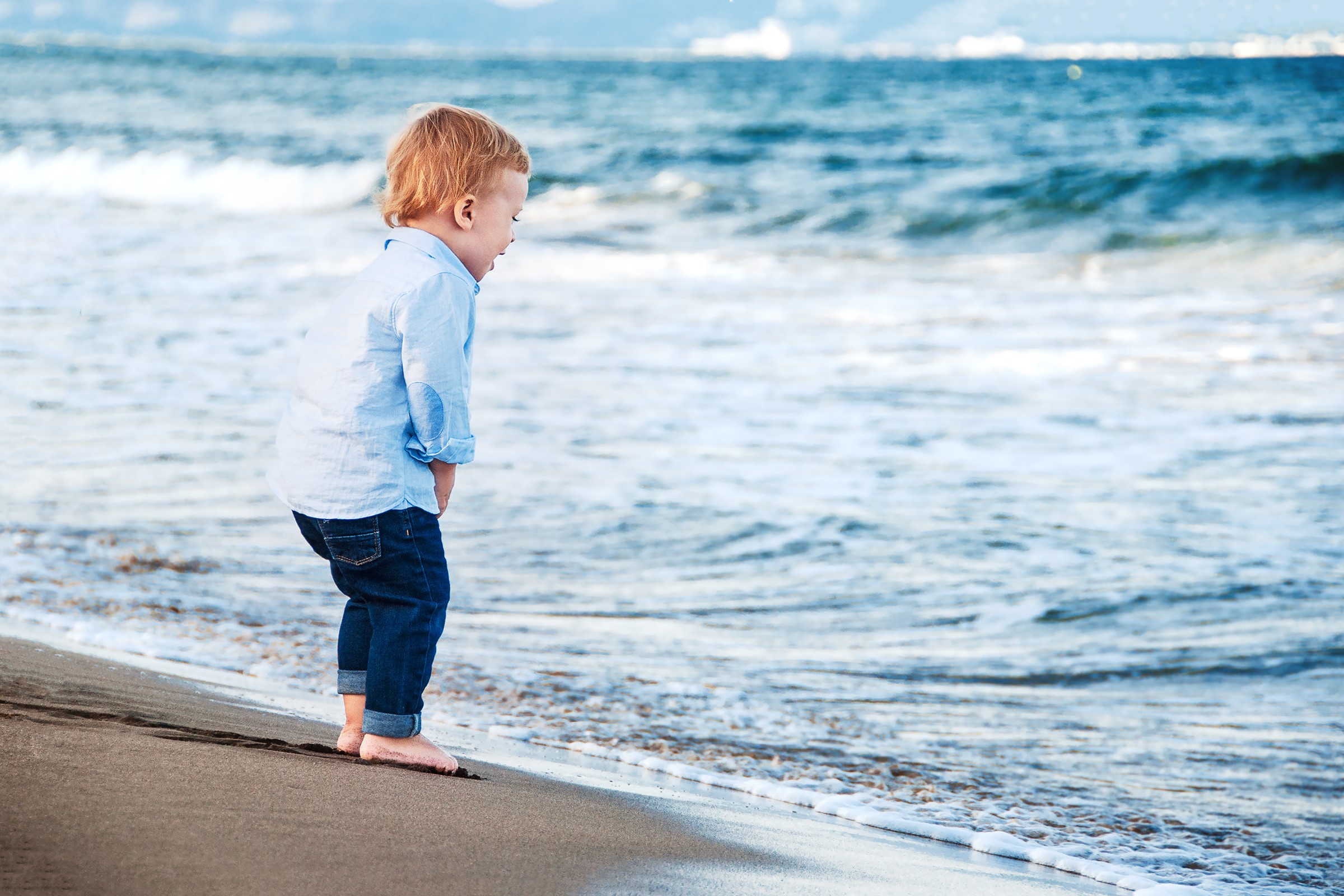 Boy in blue shirt and jeans on a beach HD Wallpaper