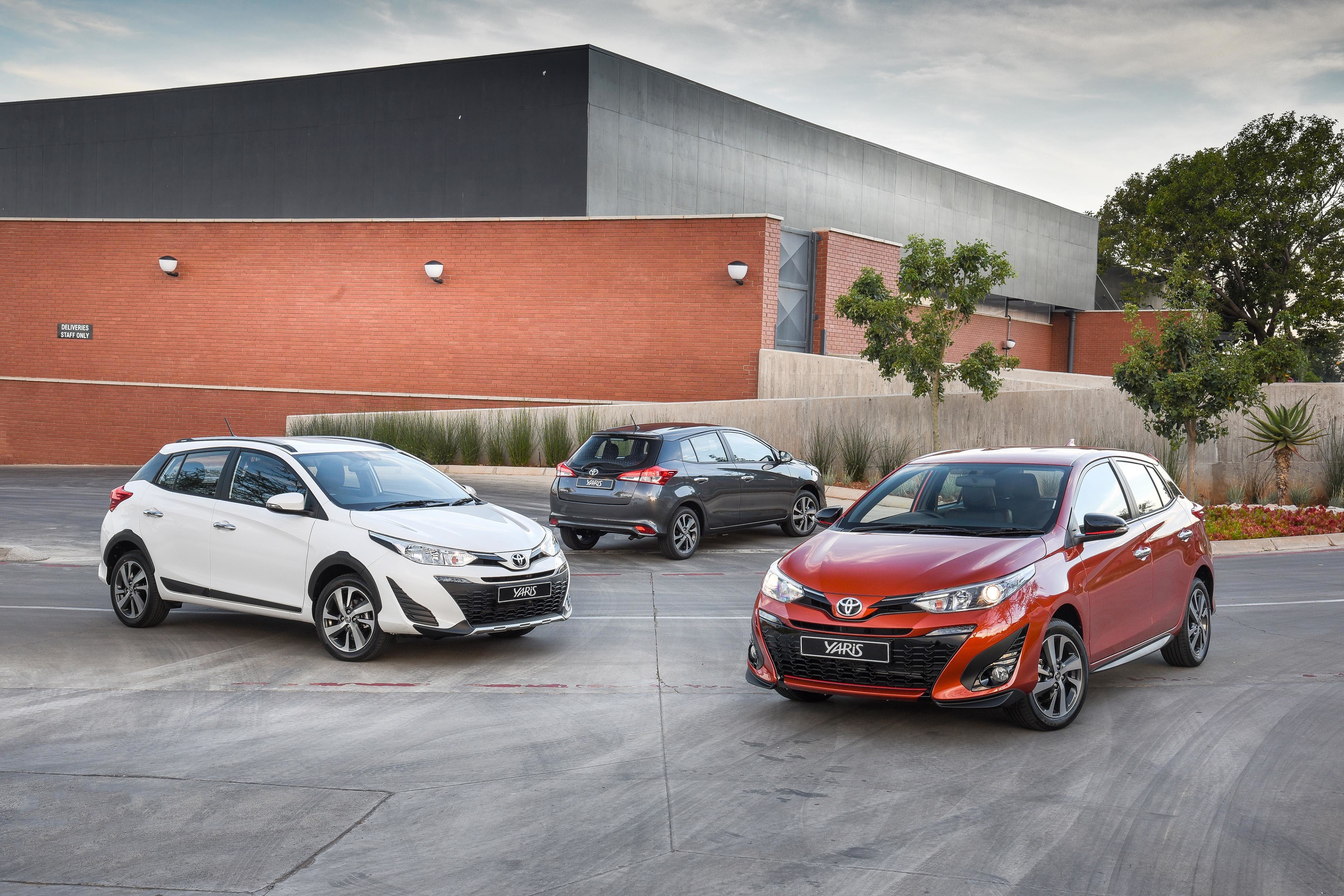 Three Toyota Yaris cars in a parking lot HD Wallpaper