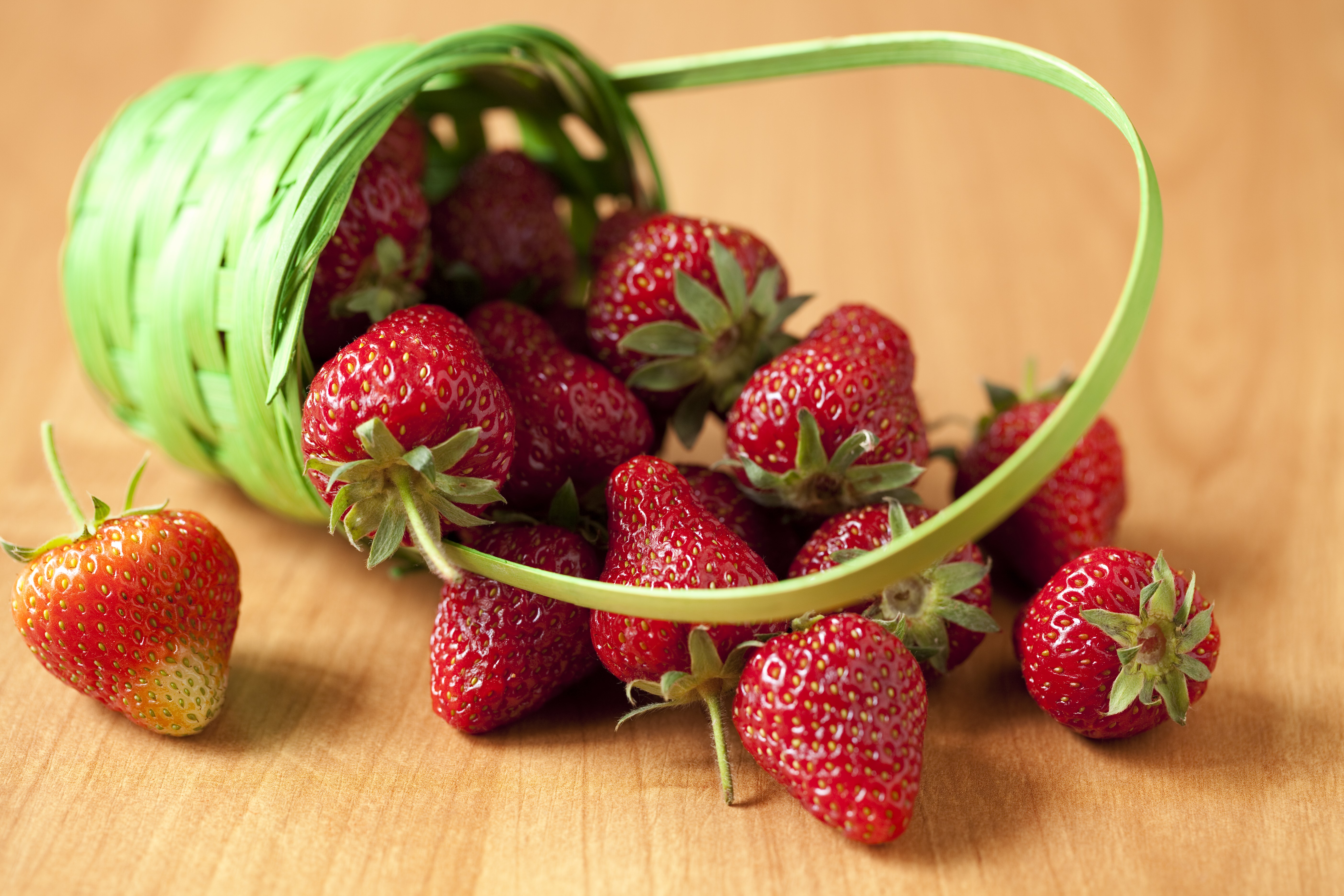 Strawberries spilling from a wicker basket HD Wallpaper