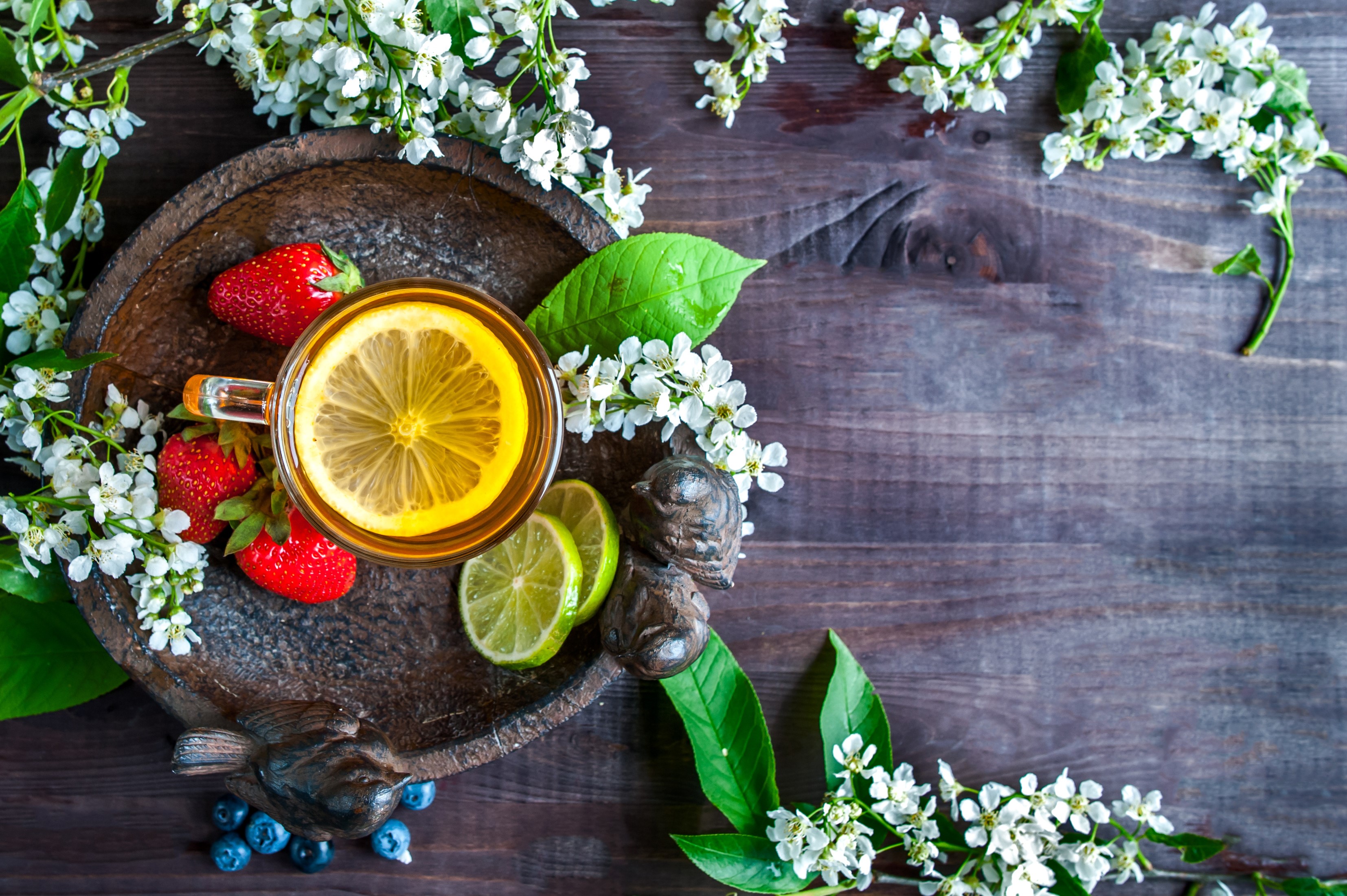 Tea with strawberries, lemon, and lime on a wooden table with flowers HD Wallpaper