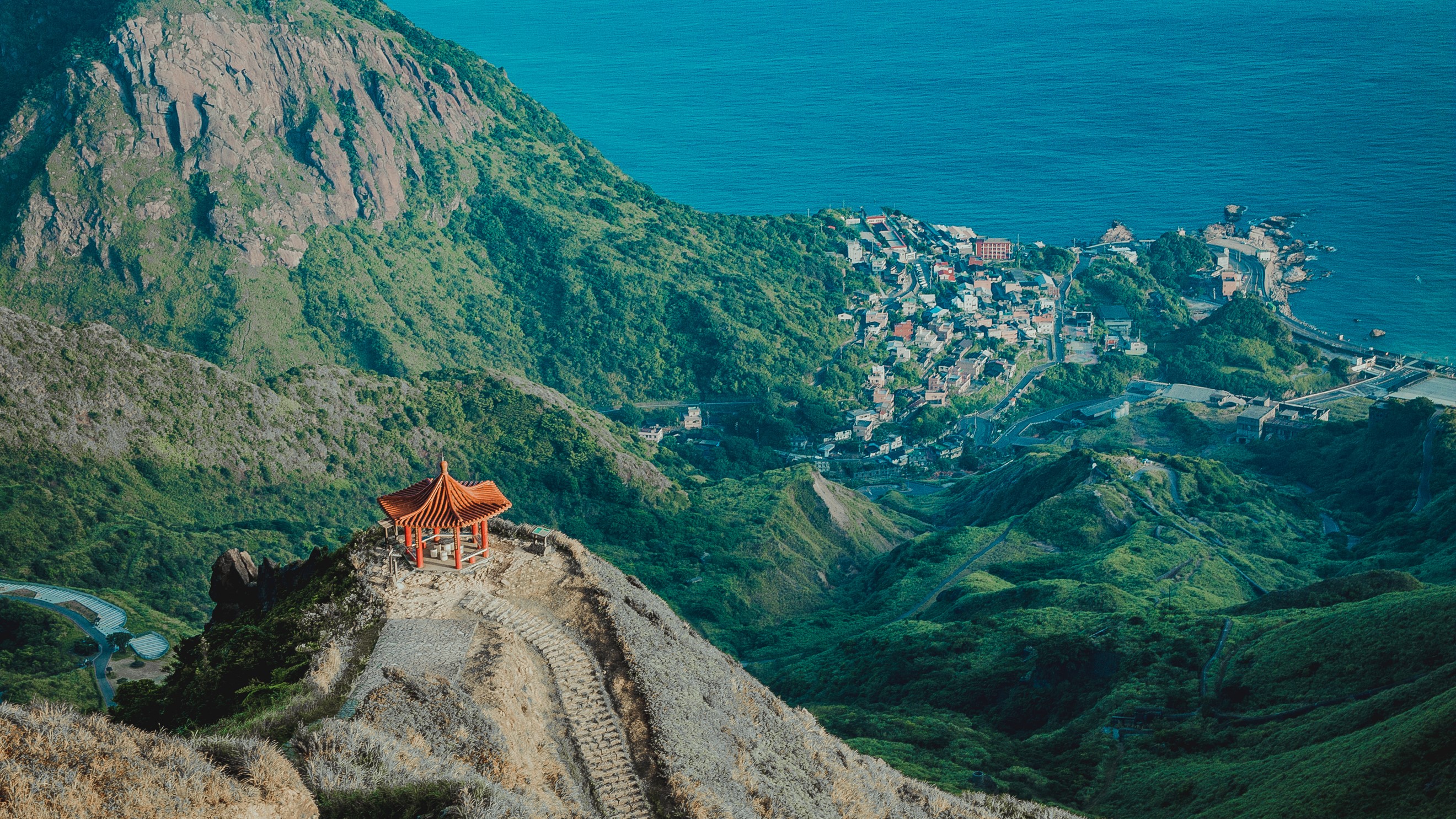Mountainous landscape with coastal town and pagoda in Taiwan HD Wallpaper