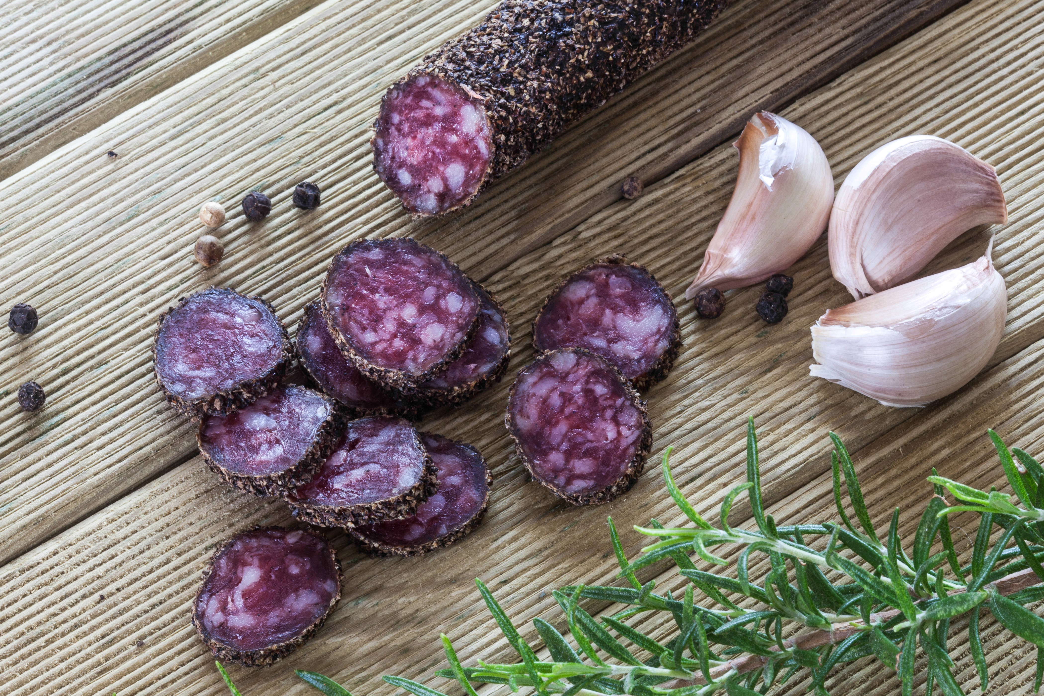 Sliced salami with garlic and rosemary on wood HD Wallpaper