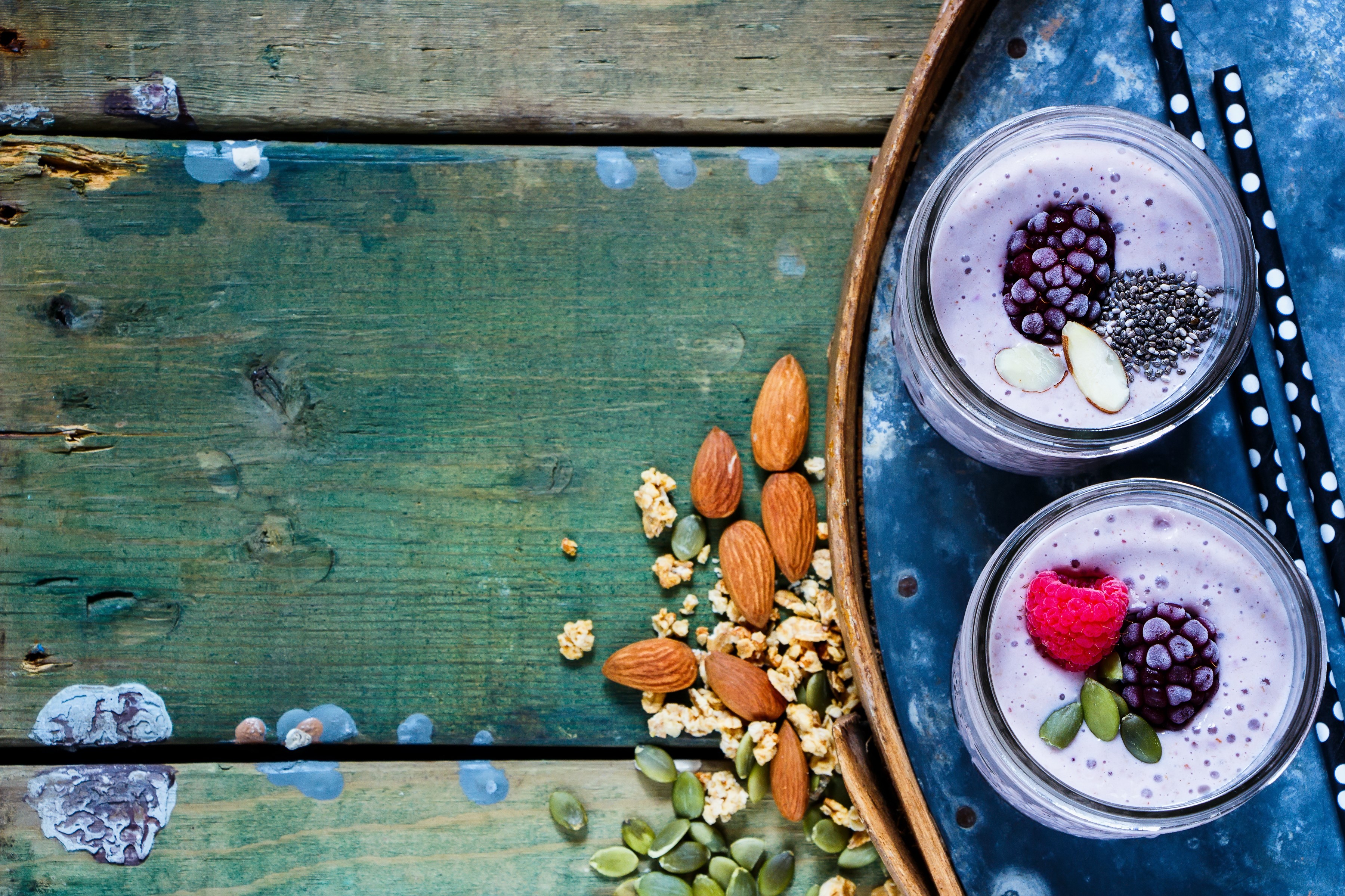 Two berry smoothies with nuts and seeds on wooden planks HD Wallpaper