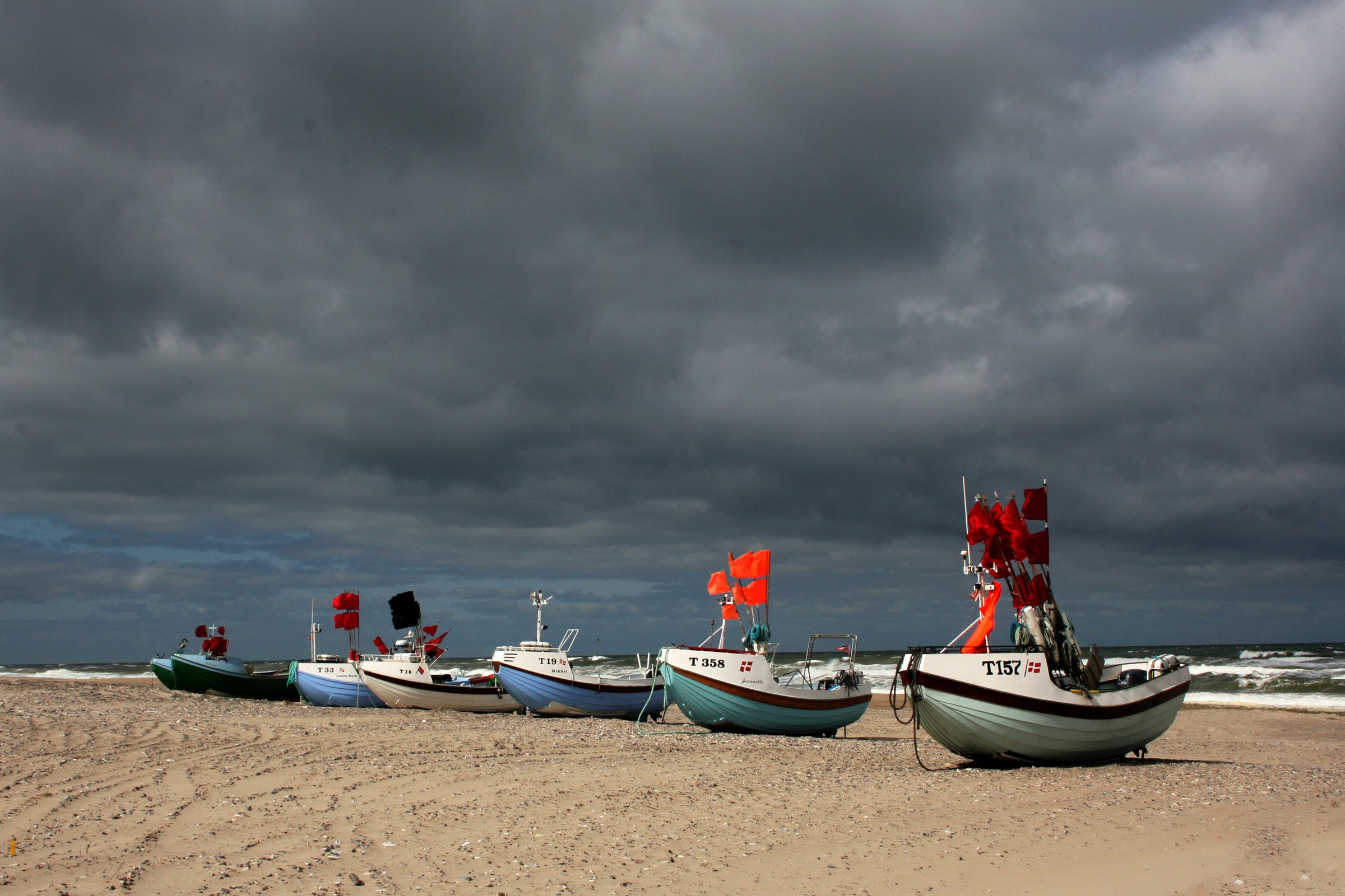 Fishing boats on a sandy beach under a stormy sky HD Wallpaper