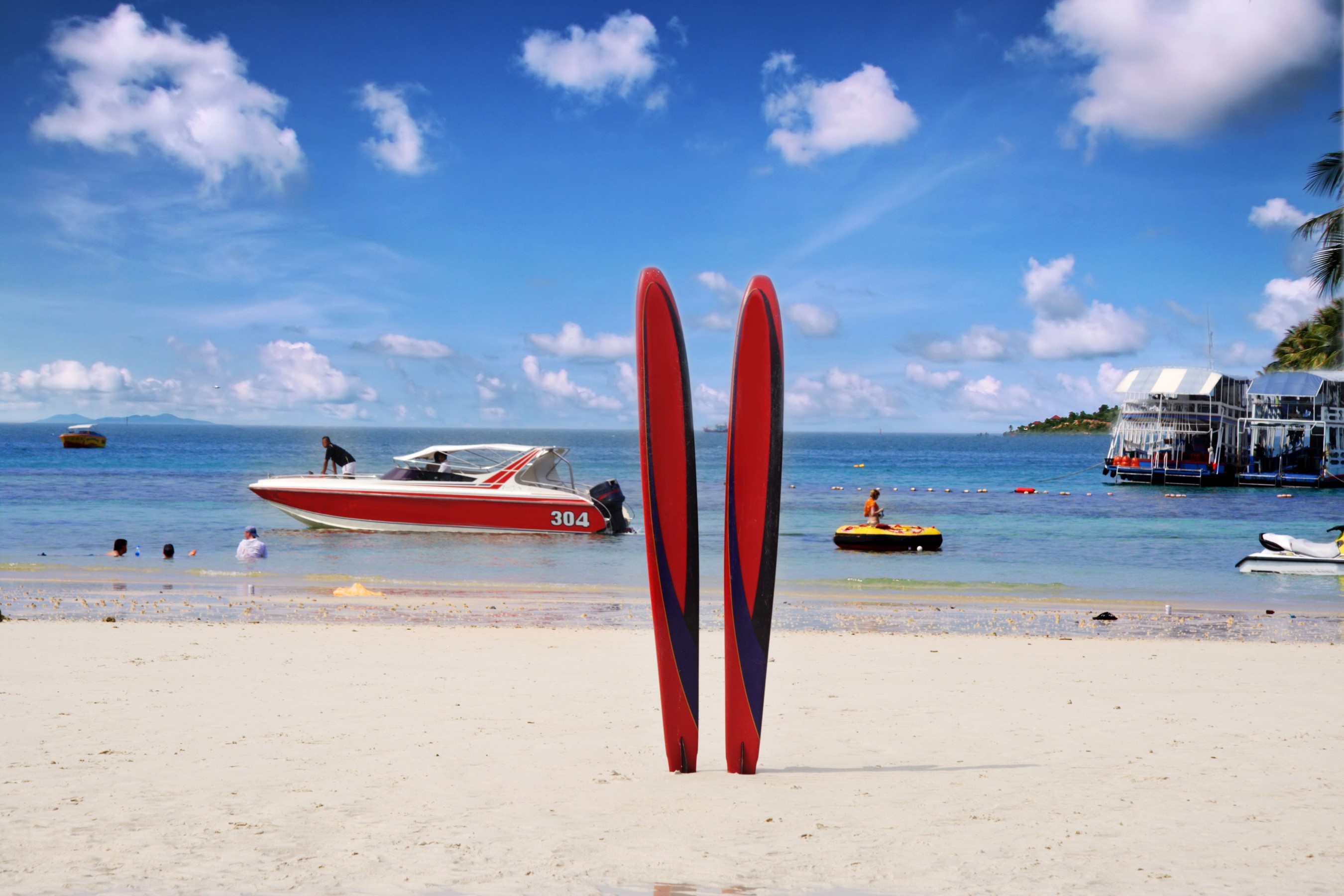 Red motorboat and surfboards on a tropical beach HD Wallpaper
