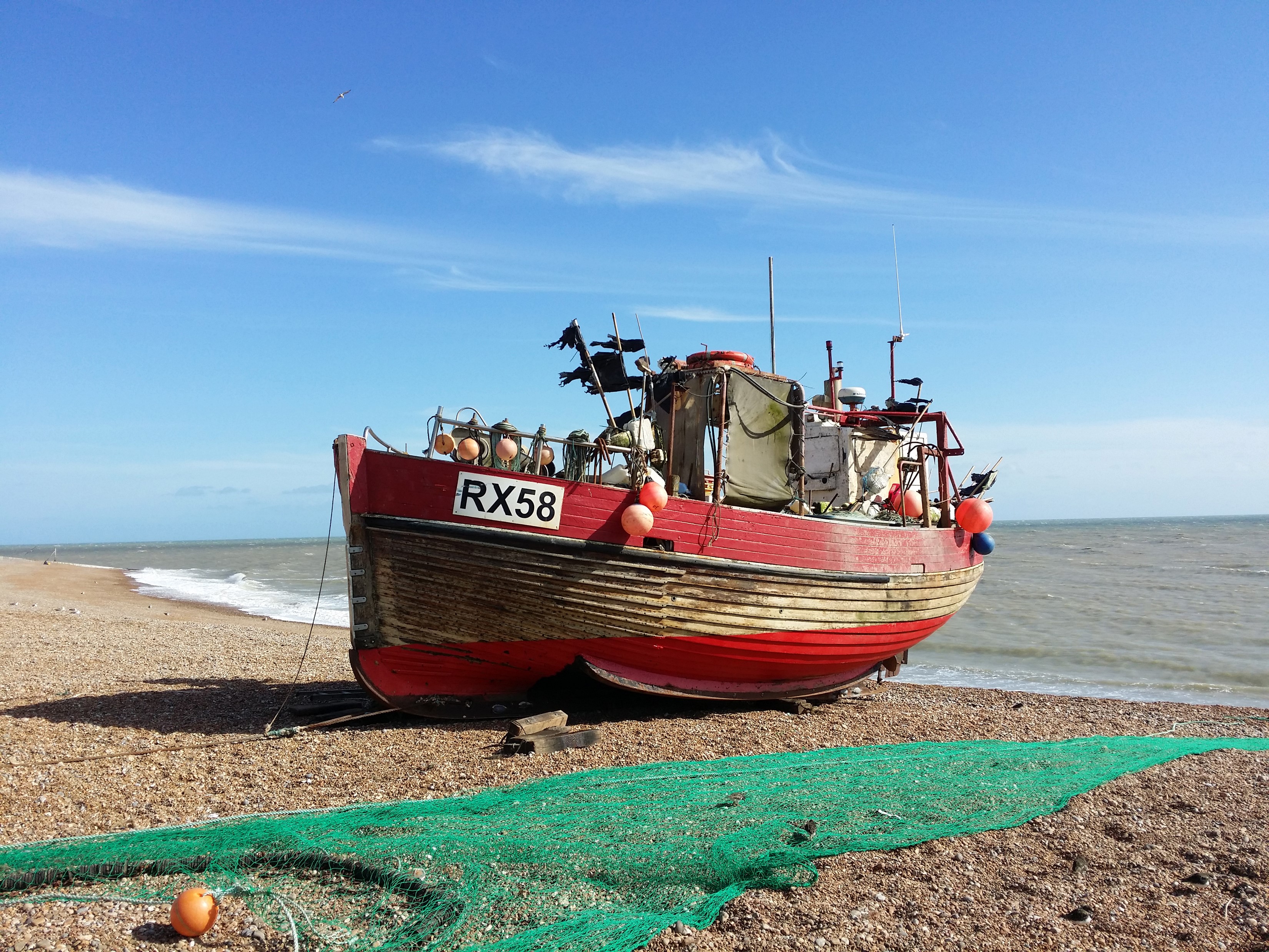 Fishing boat RX58 on a pebble beach HD Wallpaper
