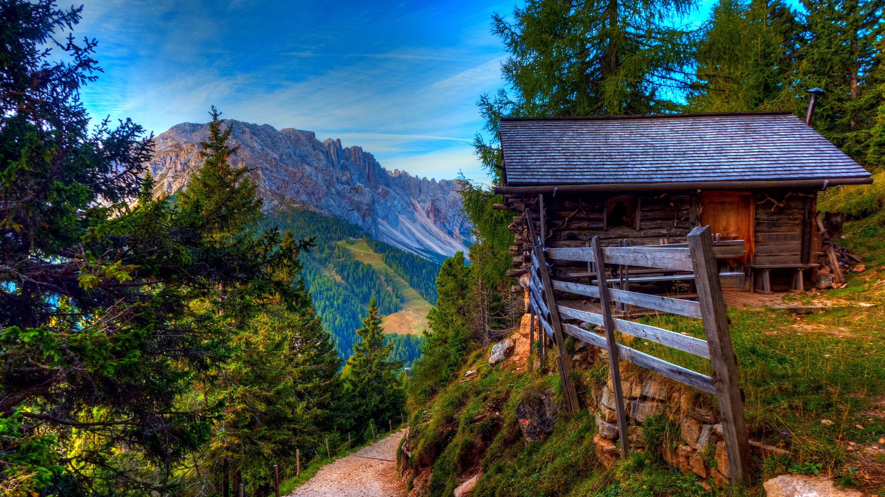 Wooden cabin on a mountain path with Alps in the background HD Wallpaper