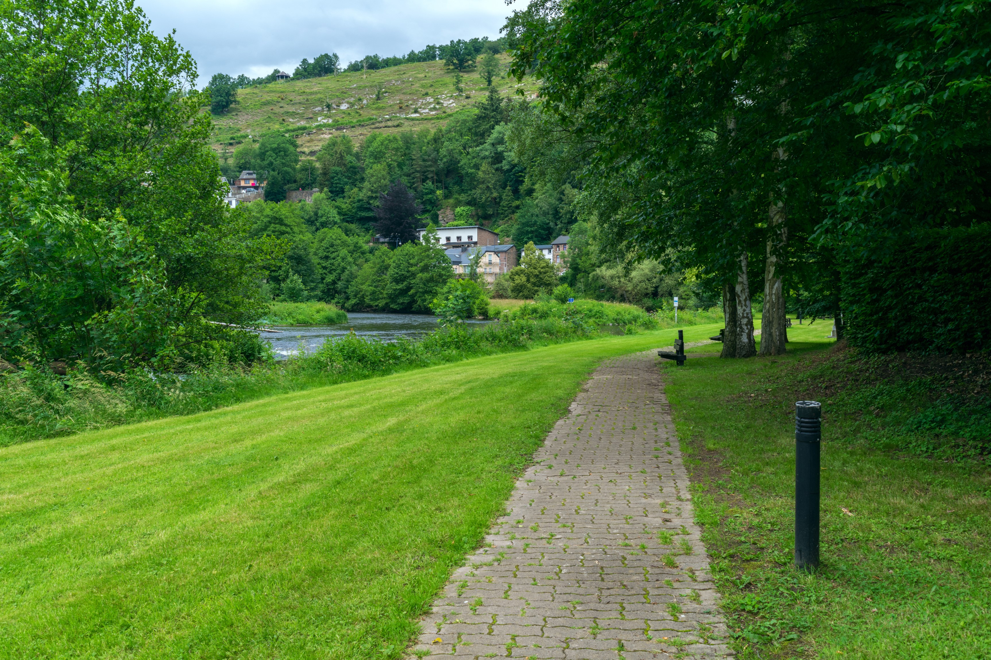 Path along a river with houses on a hill in Laroche, Belgium HD Wallpaper