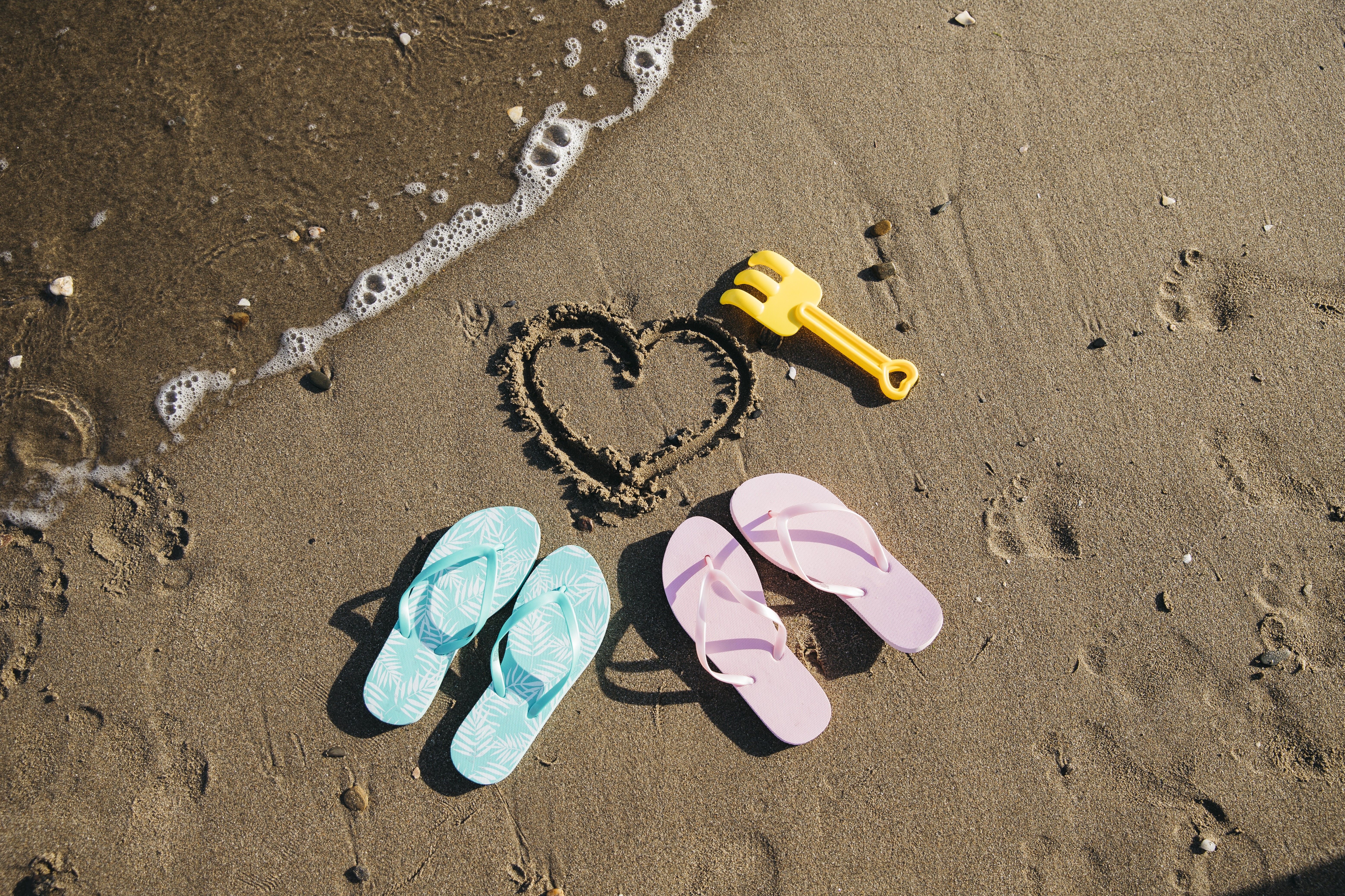 Heart drawn in sand with flip-flops and rake HD Wallpaper