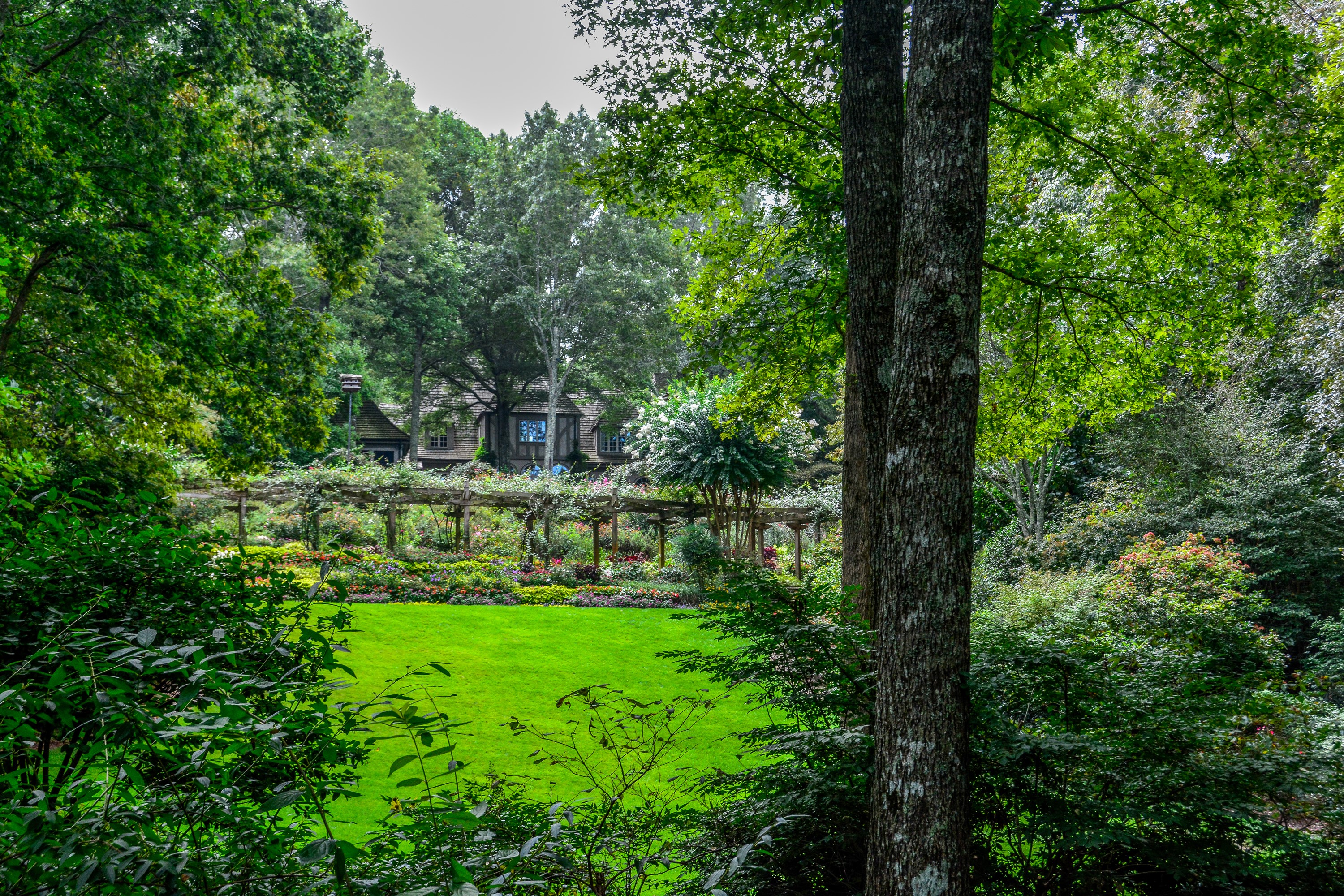 Gibbs Gardens with a house and pergola HD Wallpaper