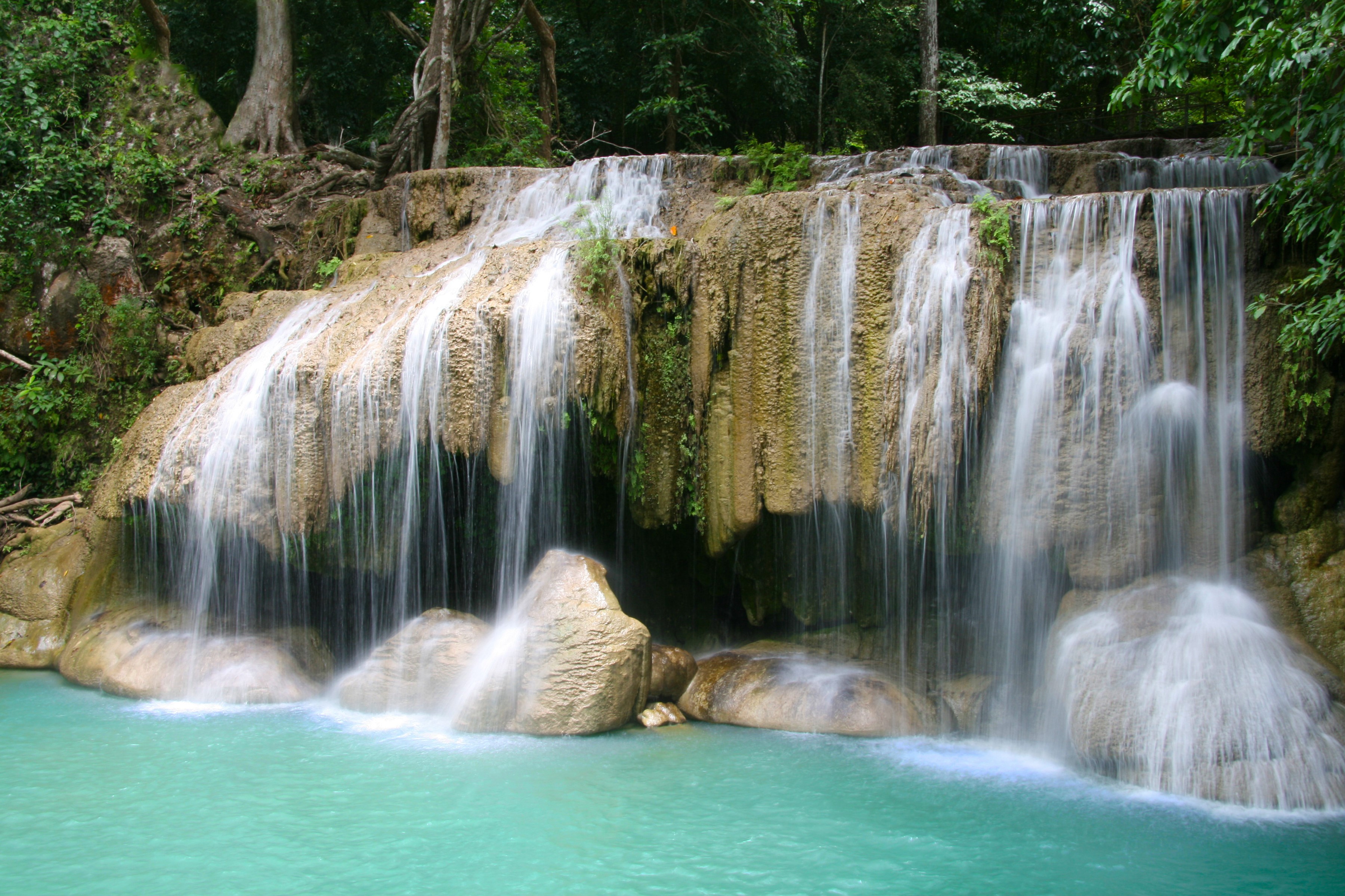 Multi-tiered waterfall cascading into turquoise water HD Wallpaper