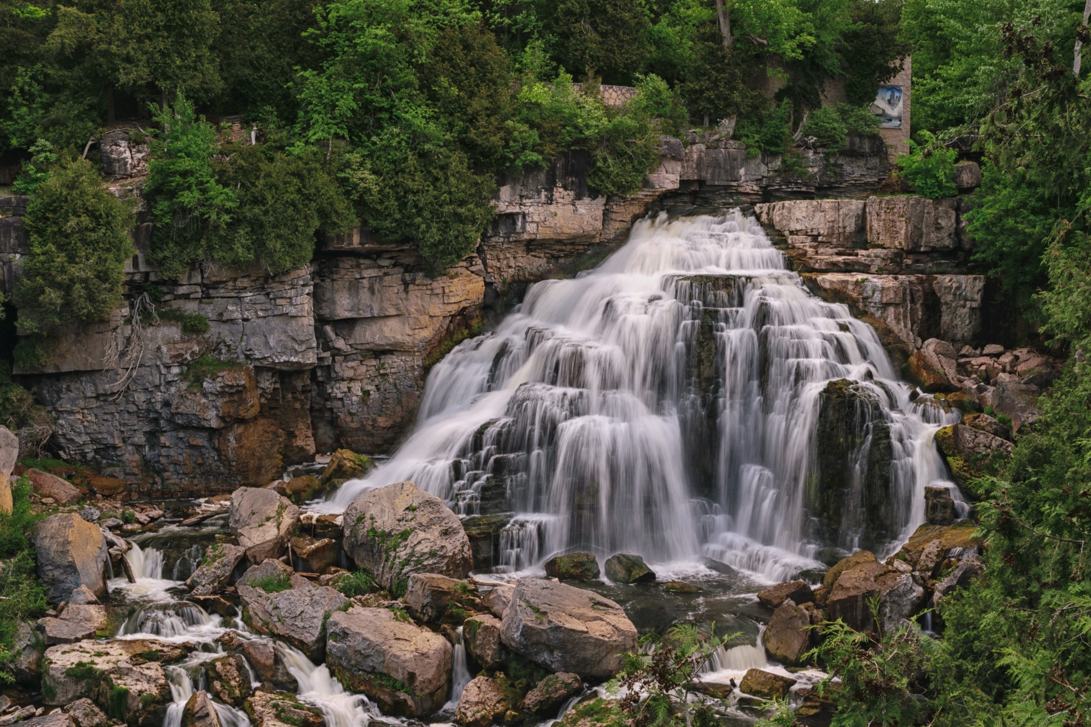 Waterfall cascading over rocks in a forest HD Wallpaper