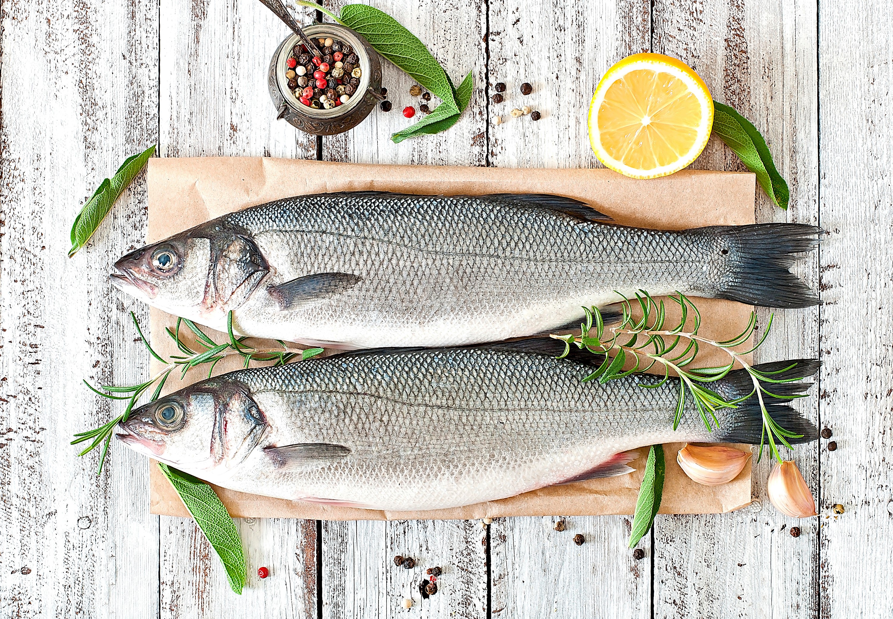 Two raw fish with lemon, garlic, and herbs on wood HD Wallpaper
