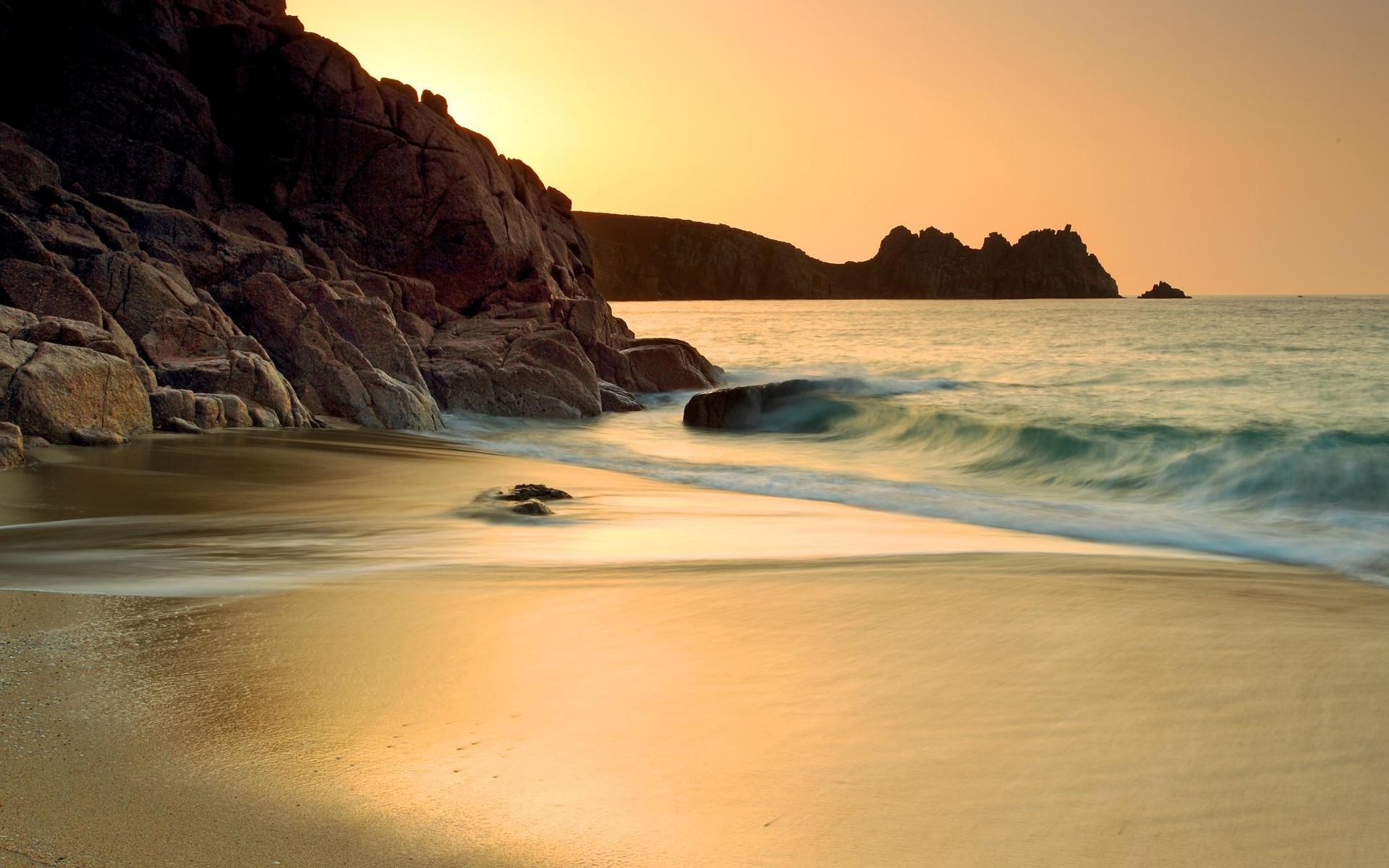 Beach with rocky cliffs and ocean at sunset HD Wallpaper