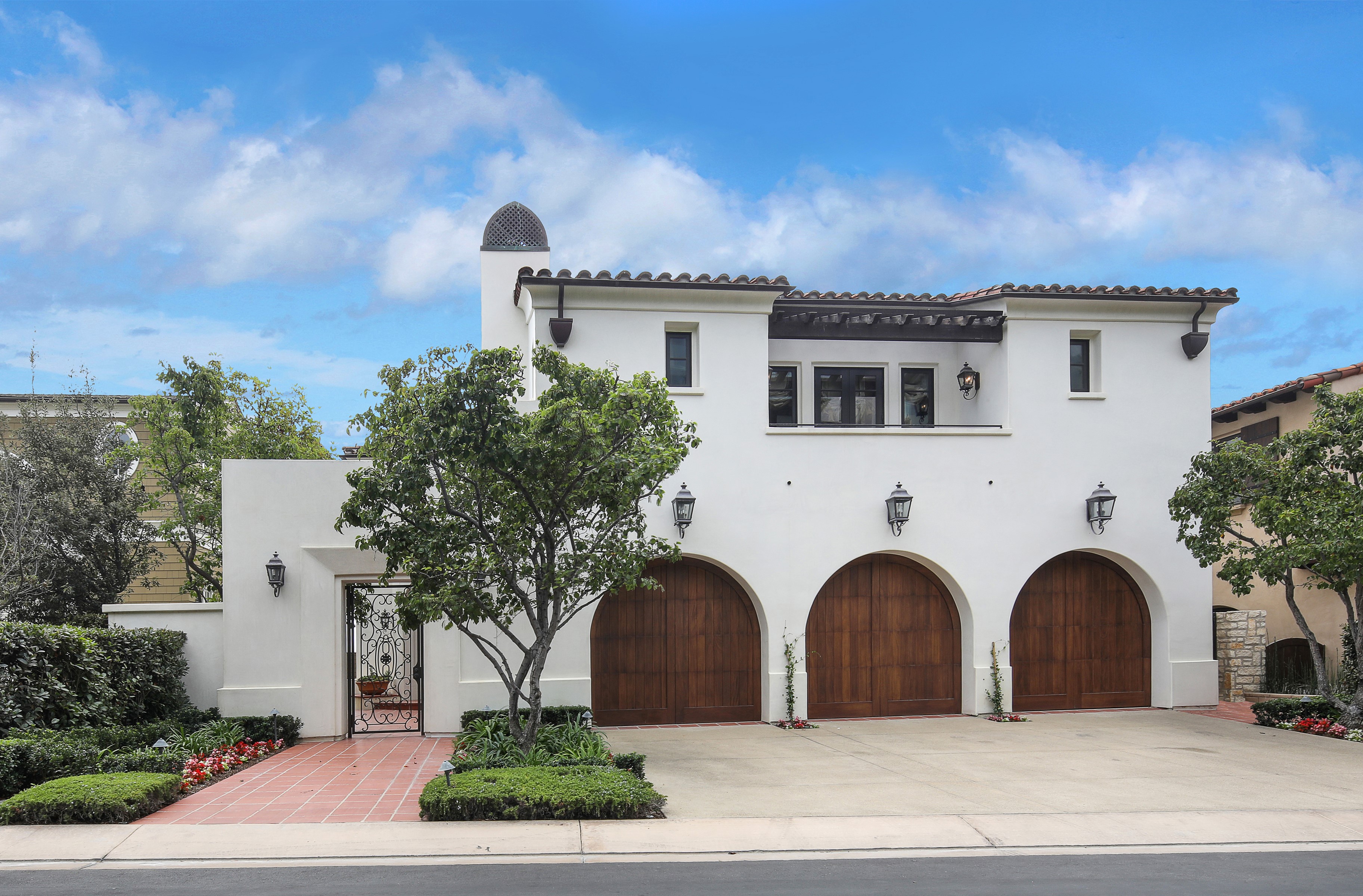 White Mediterranean-style house with arched garage doors and a courtyard gate HD Wallpaper