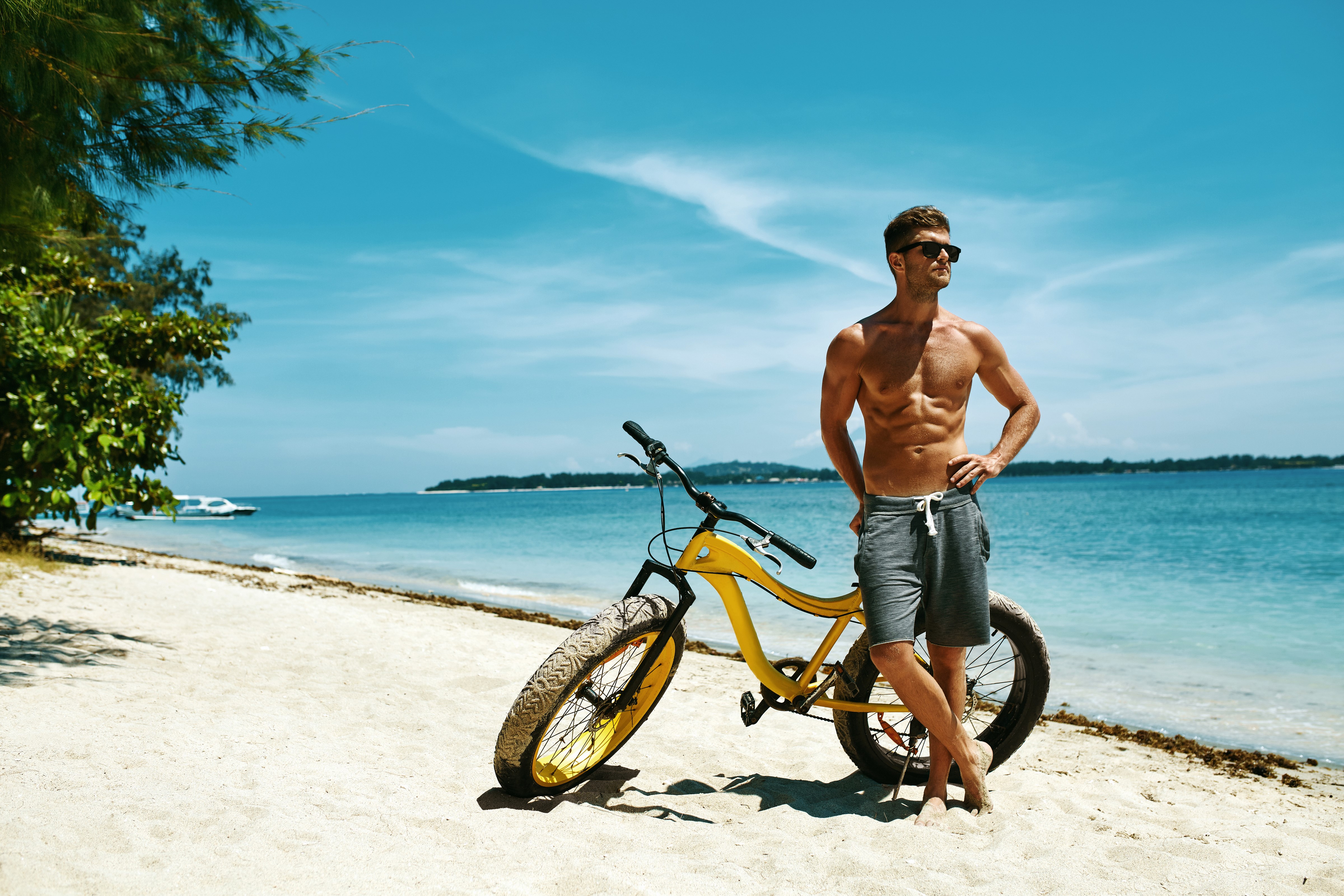 Man with sunglasses and bicycle on beach HD Wallpaper