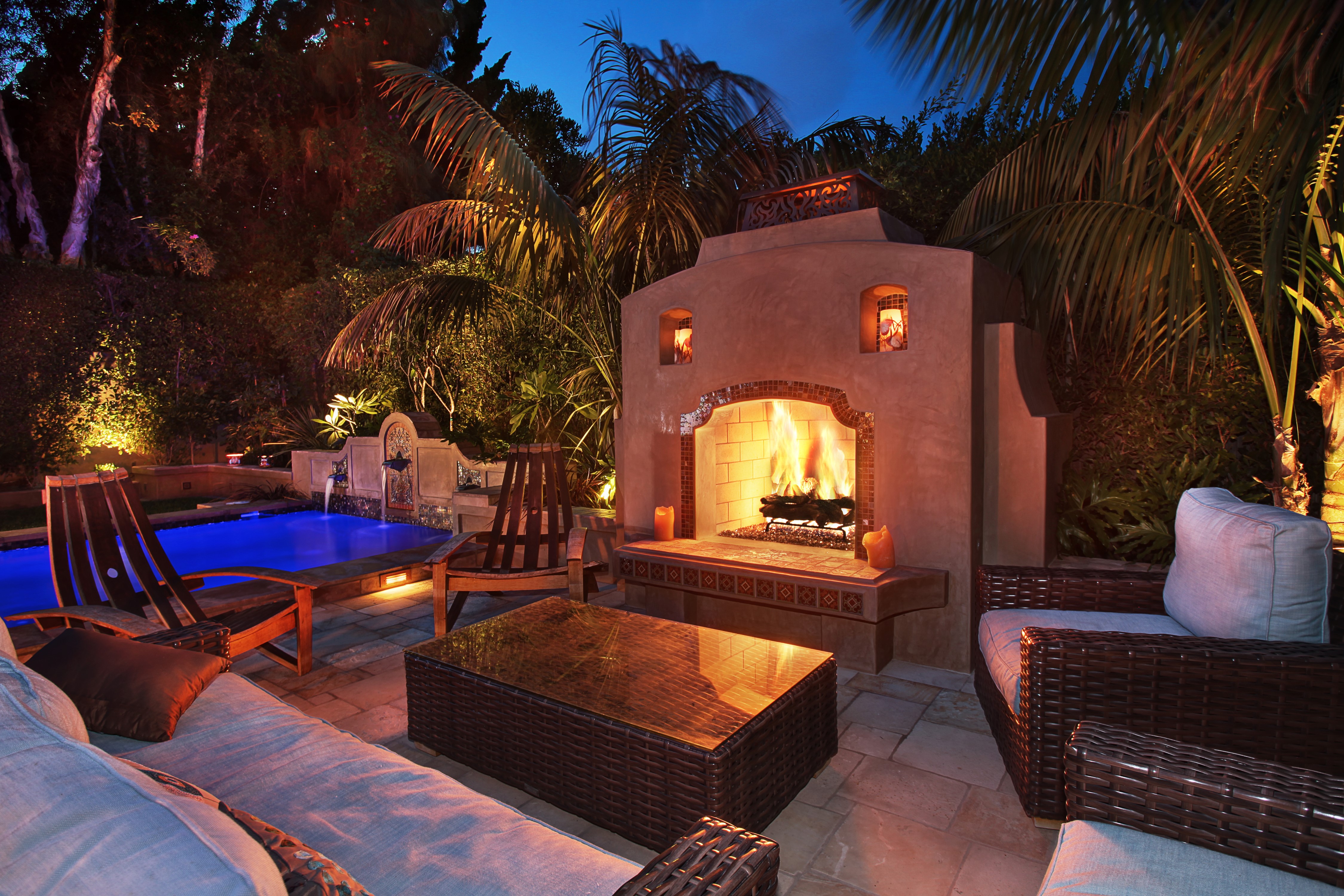 Outdoor patio with pool and fireplace at dusk HD Wallpaper